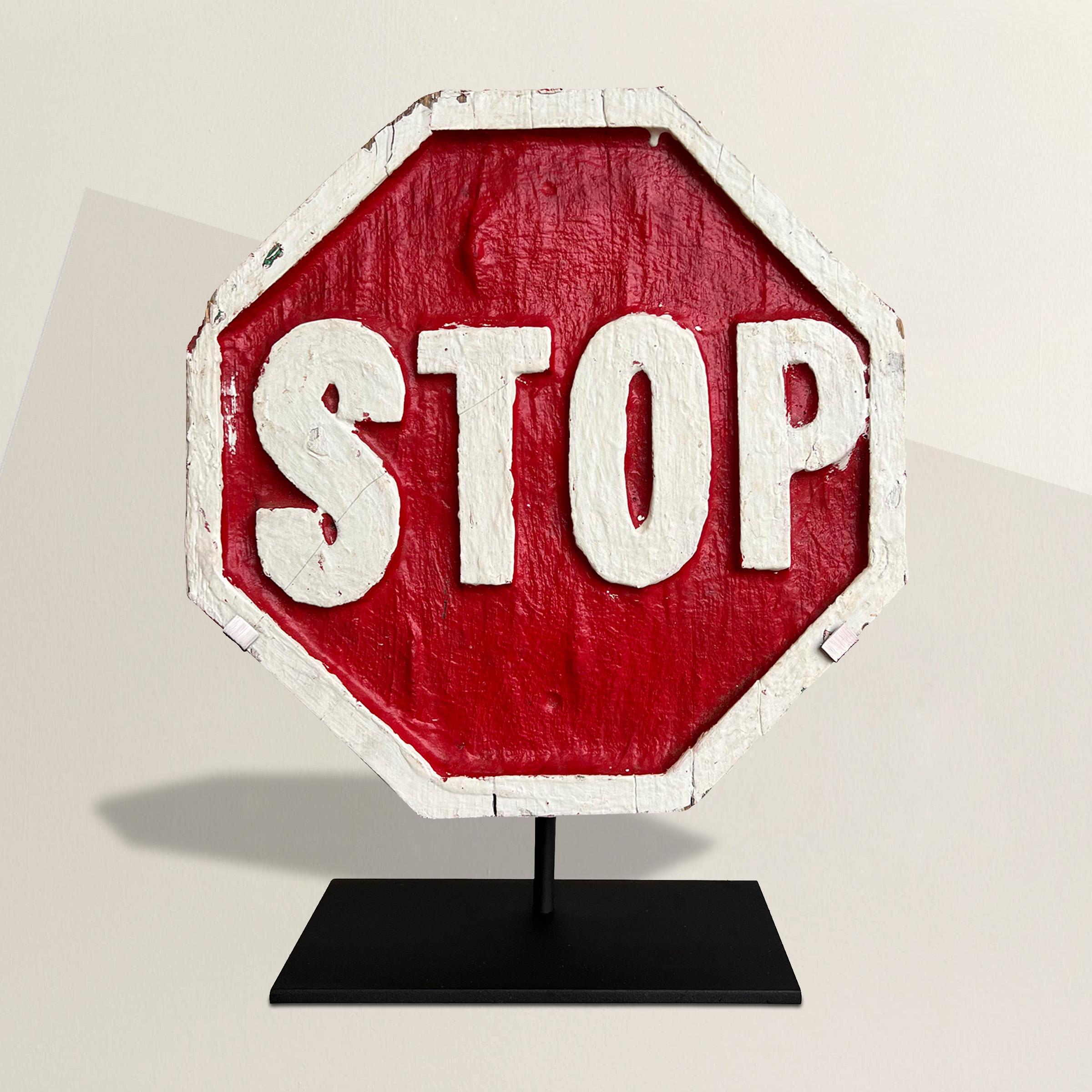 A 20th century American Folk Art hand-carved and painted wood stop sign mounted on a custom steel stand.