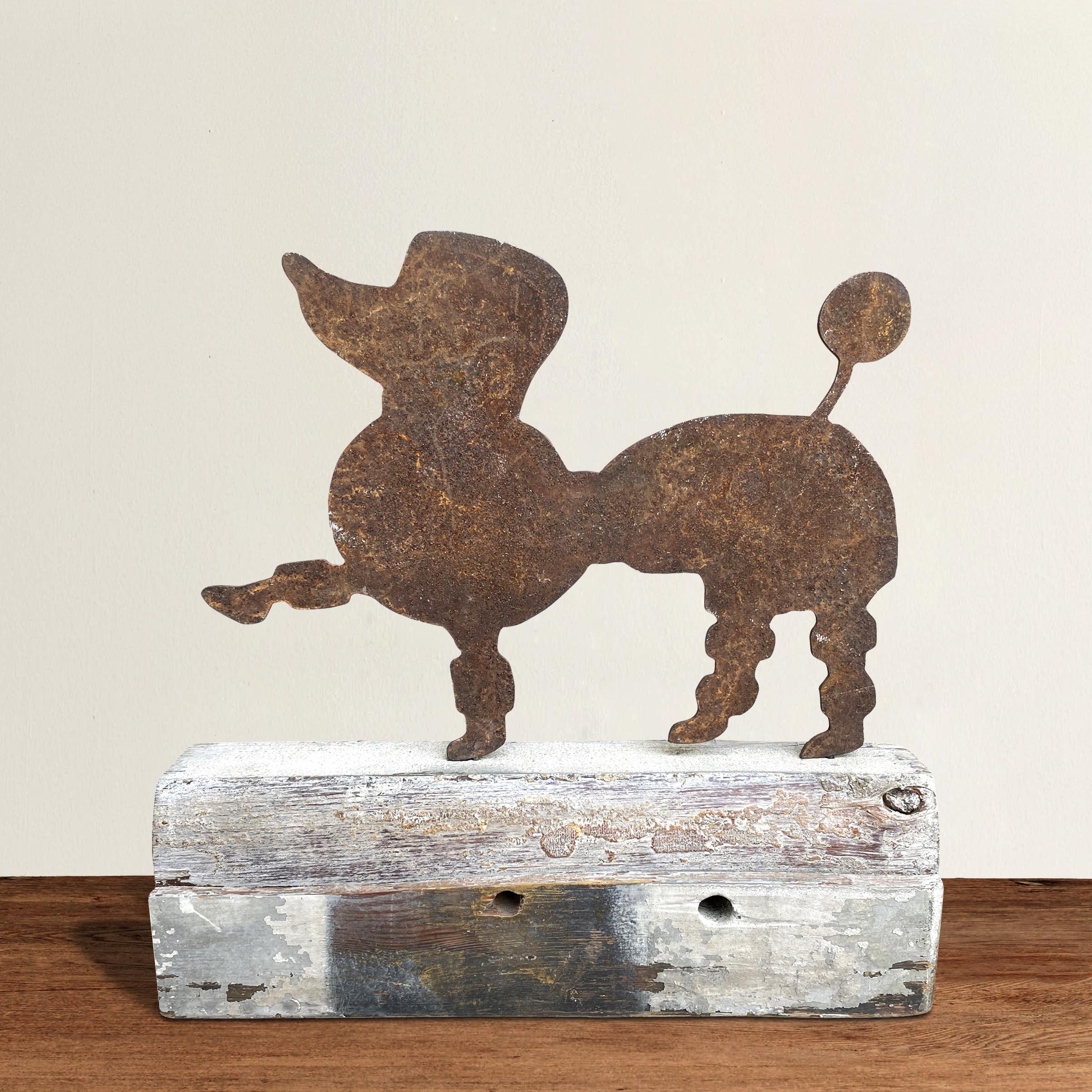 A charming 20th century American Folk Art poodle sculpture constructed from a cut iron poodle silhouette mounted to an architectural painted wood remnant.