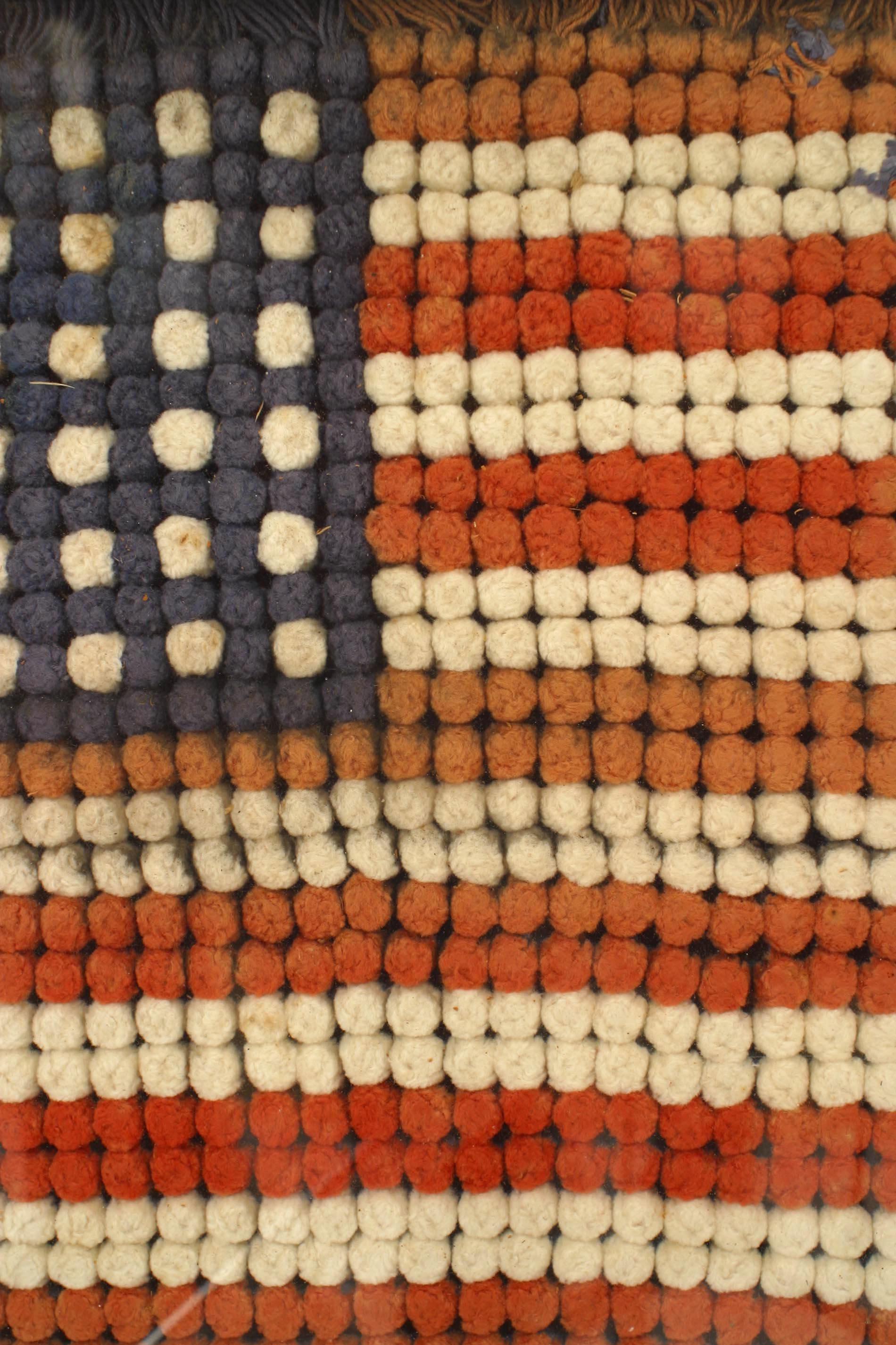 American Country (early 20th Century) folk art embroidery of a US flag portrayed with small pompoms in a wood frame behind glass.