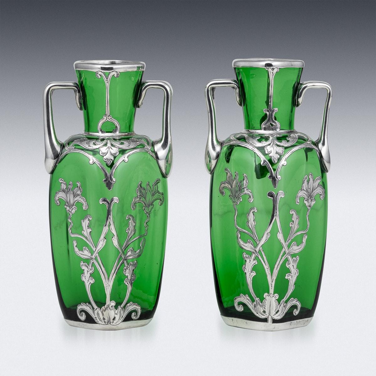 Antique 20th Century Art Nouveau green glass vases, crafted in a typical Alvin style. Adorned with delicate silver flowers and handles, these American urns add a touch of elegance to any space. A charming decorative piece suitable for any home