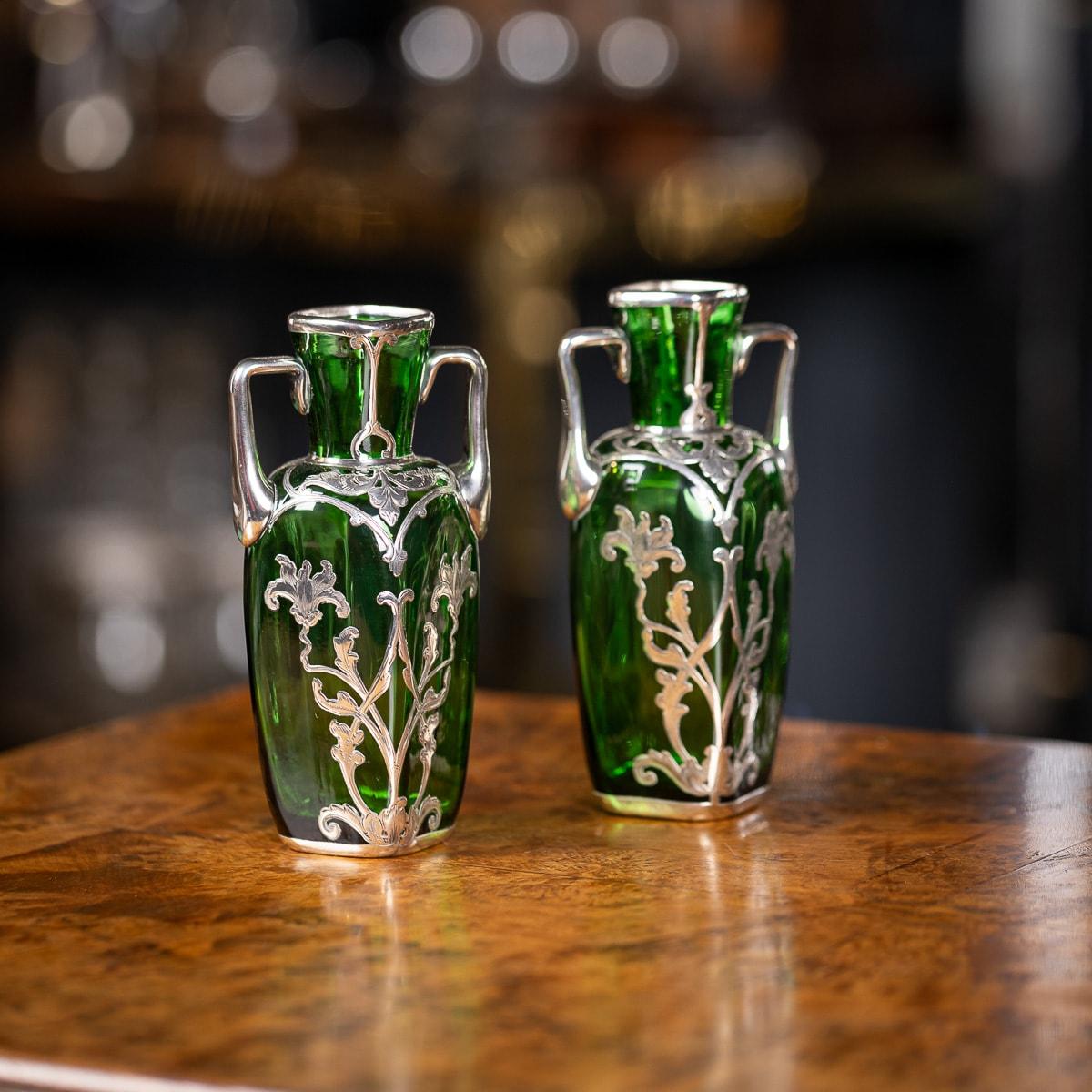 Antichi vasi in vetro verde Art Nouveau del XX secolo, realizzati nel tipico stile Alvin. Elegate con delicati fiori e manici in argento, queste urne americane aggiungono un tocco di eleganza a qualsiasi spazio. Un affascinante pezzo decorativo