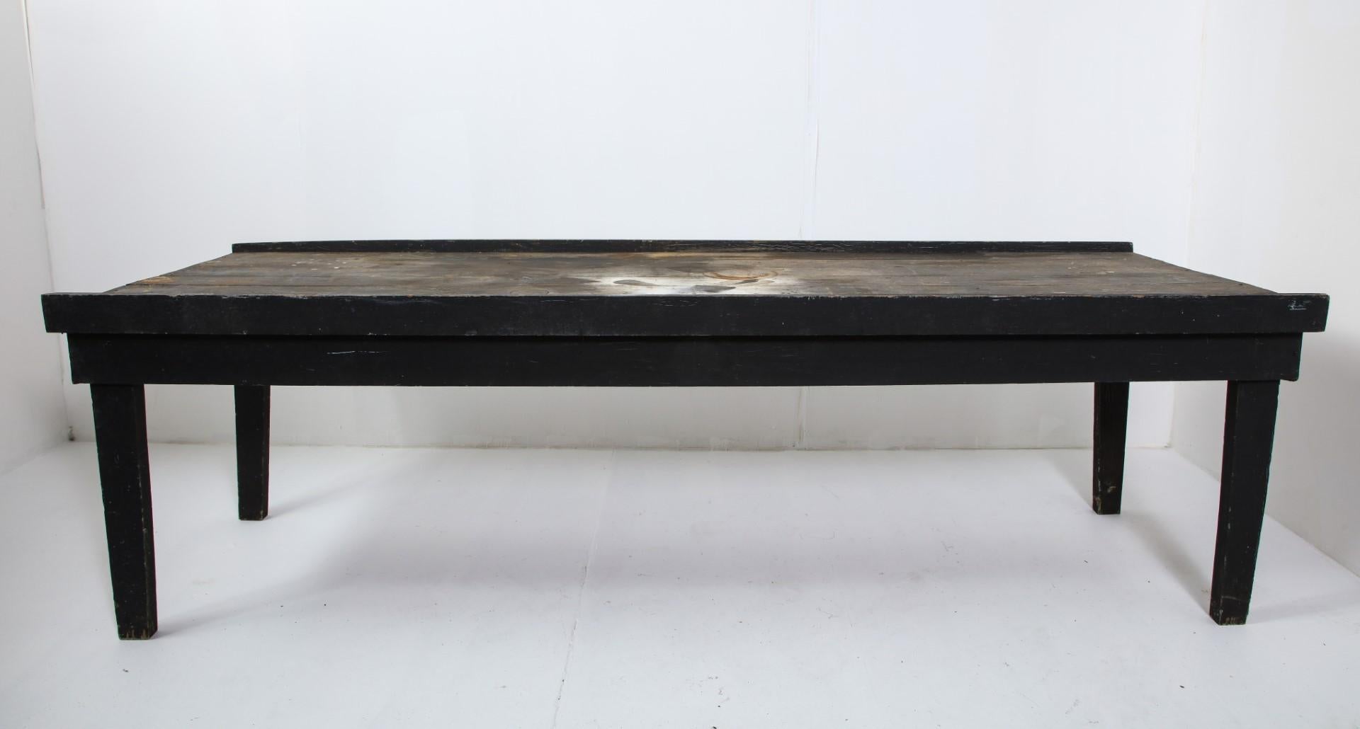 Table primitive américaine du début du 20e siècle en chêne peint en noir. Le dessus est marqué par des cercles d'eau, de la peinture en spray, une usure de surface. Idéal pour une table de travail ou un usage extérieur.
