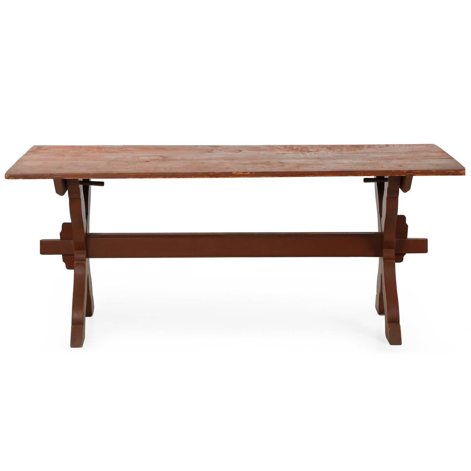 This handcrafted trestle table is a clean and simple design, the entire table breaking down for easy movement and storage. Each X-form leg separates into two pieces, the single stretcher joining through these with a long tenon that projects through