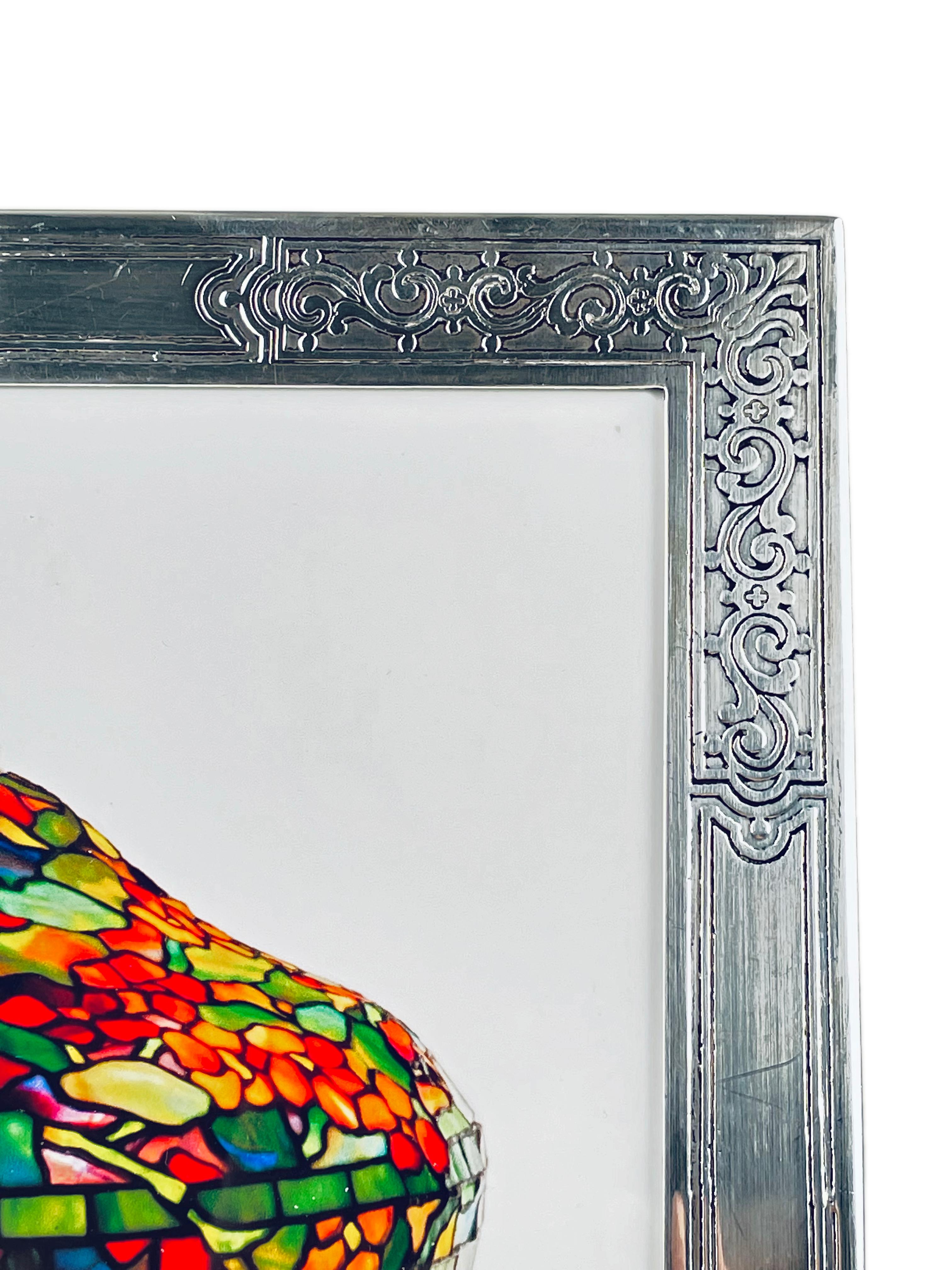An early 20th century American Art Nouveau sterling silver and wood picture frame by, Tiffany & Co. with hand chased scroll motif throughout, without monogramming, retains its original wood and sterling back. The frame is marked 