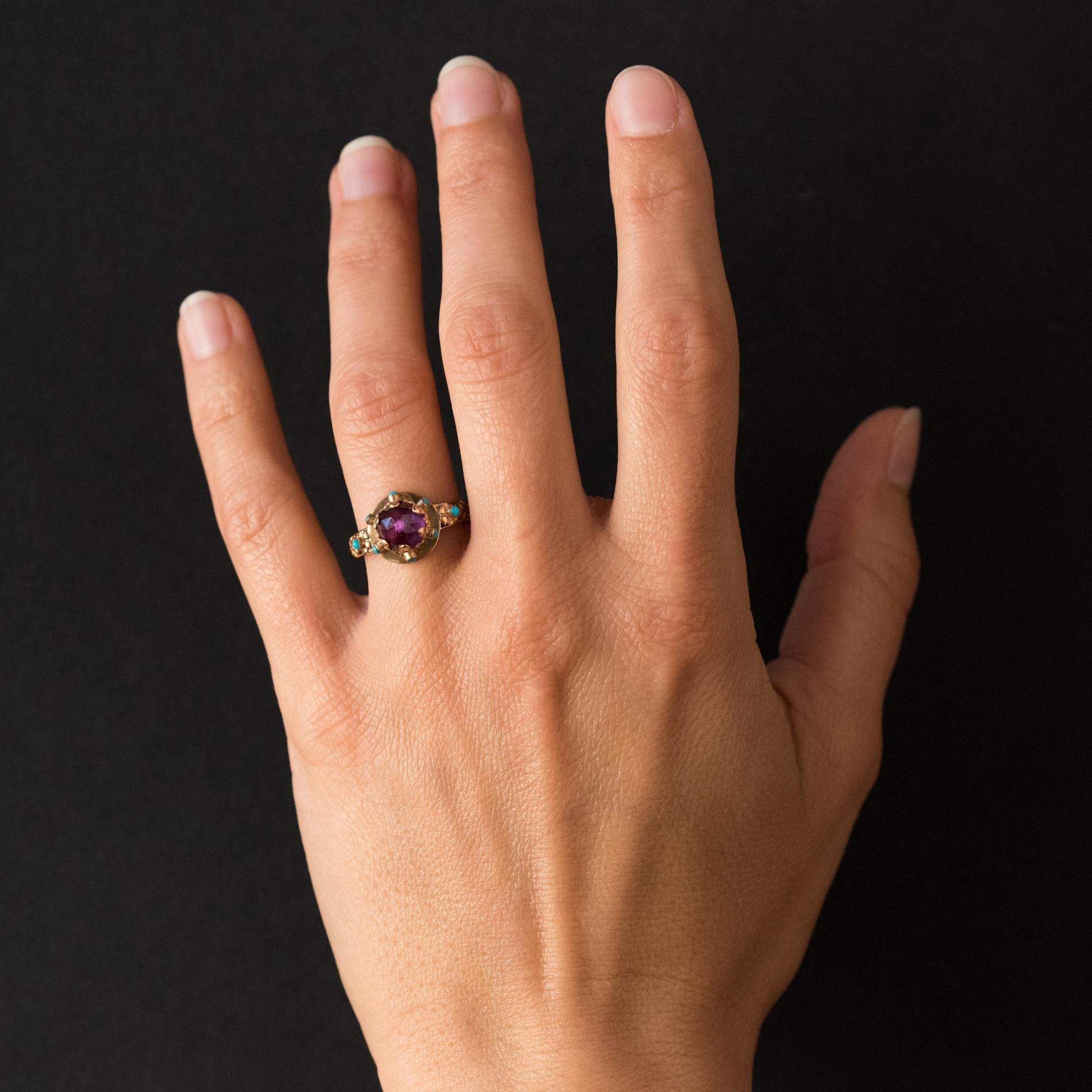 Ring in 20 karats yellow gold.
This charming antique ring is set on its top of an amethyst briolette. The stone is set with claws each adorned with a fleur- de- lys pattern and set with a turquoise. On either side, on the departure of the ring, is a