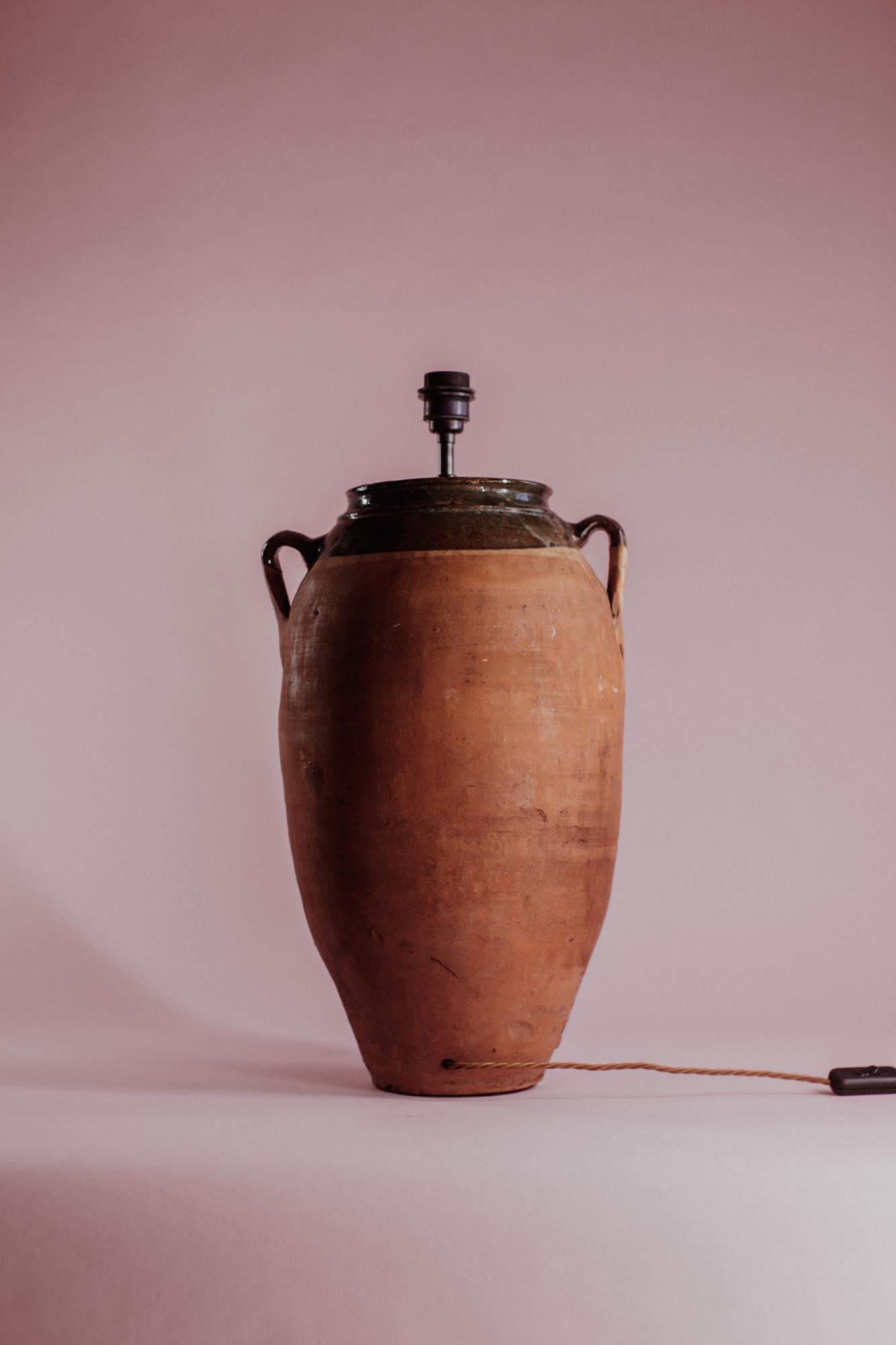 Ce pot en terre cuite anatolien du XXe siècle se distingue par son élégant bord à glaçure verte, un détail vibrant qui complète sa base rustique en terre cuite. Fabriqué en Turquie, ce pot servait autrefois de récipient fonctionnel pour conserver