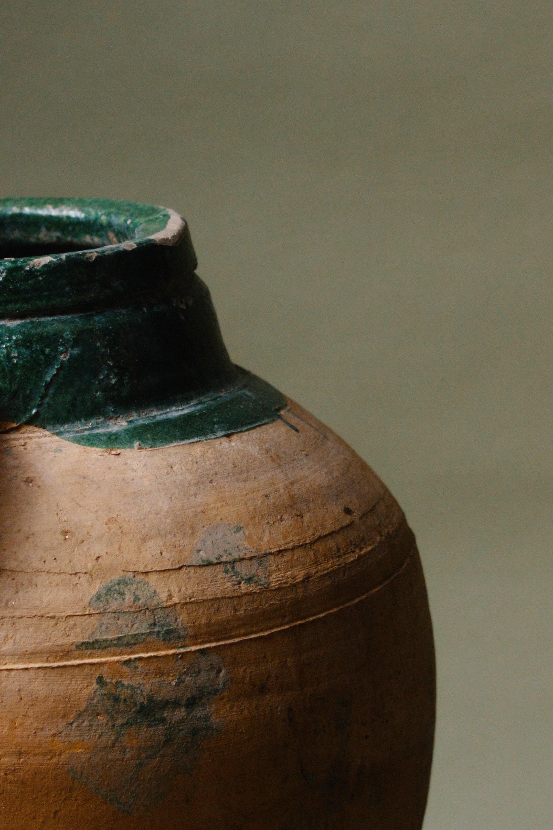 Ce récipient en terre cuite d'Anatolie du XXe siècle témoigne de la richesse du patrimoine et de la tradition artisanale de la région. Le bord émaillé vert contraste magnifiquement avec le corps en terre cuite, mettant en valeur un mélange