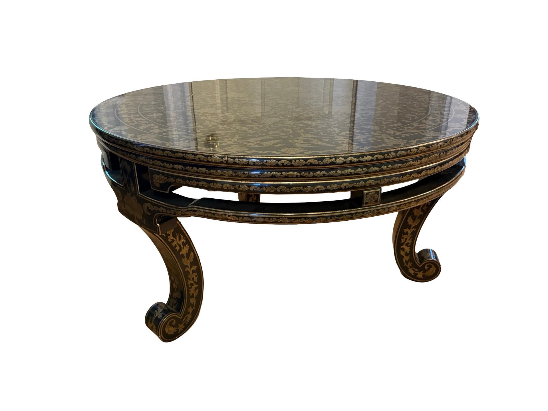 Mesa de centro circular de estilo angloindio de mediados y finales del siglo XX, finamente elaborada, que destaca por la excepcional decoración de su superficie y su composición arquitectónica formal. Totalmente lacado en negro con adornos dorados,