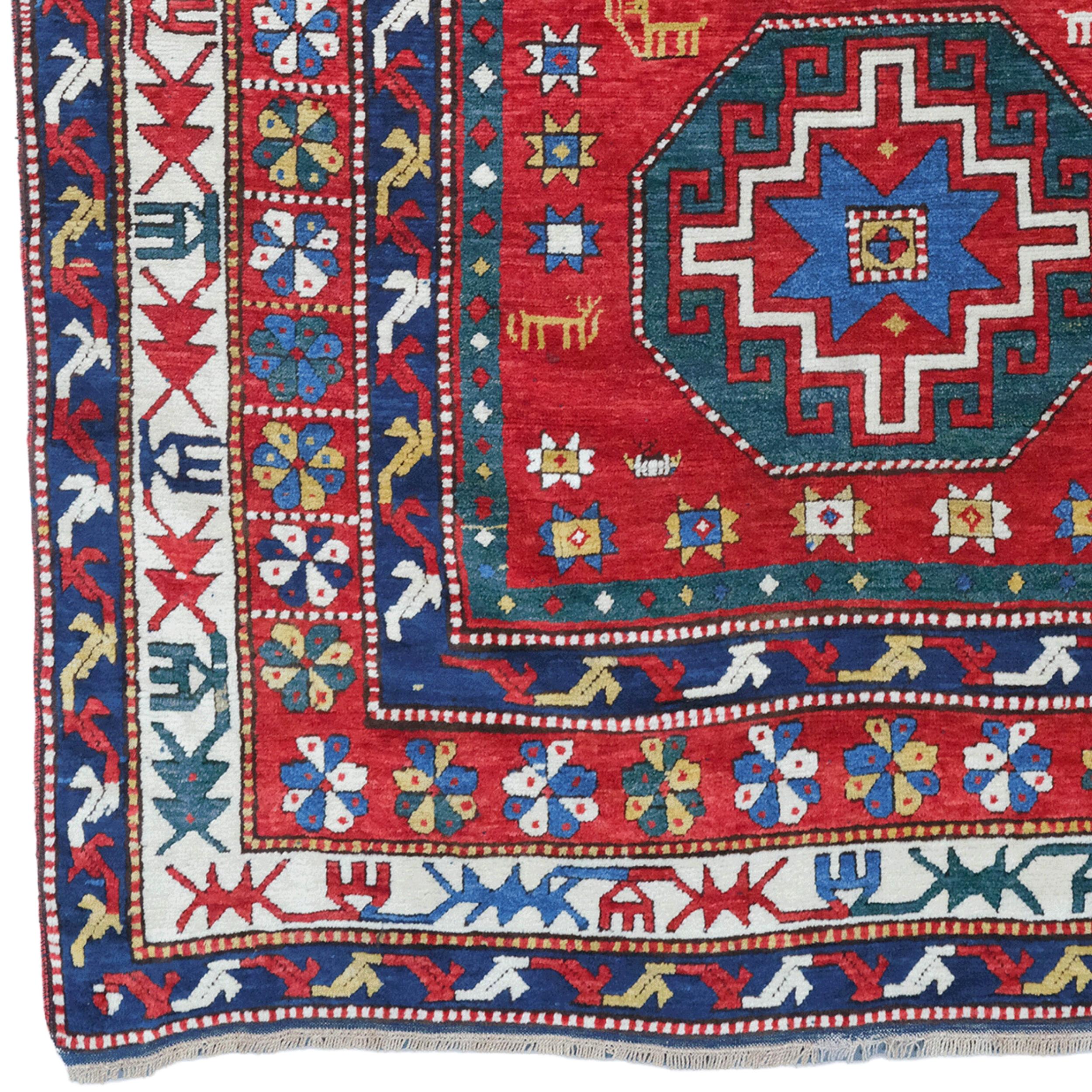 Ce tapis caucasien antique date du début du XXe siècle et se distingue par sa riche palette de couleurs et ses motifs complexes. Le centre du tapis est décoré de trois grands motifs octogonaux. Ces motifs sont dans les tons rouge, bleu et vert, et