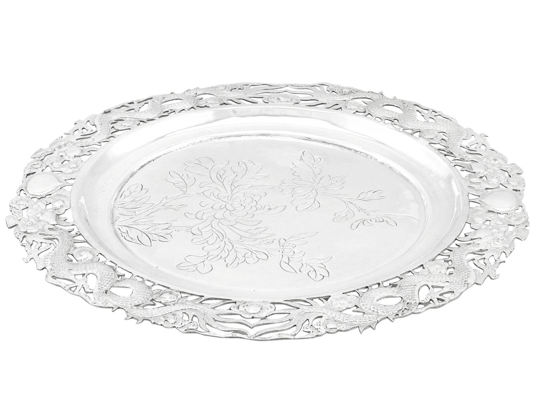 This impressive antique Chinese Export Silver (CES) salver has a circular shaped form.

The centre of the salver is embellished with an engraved chrysanthemum floral design.

The raised swept, plateaued border is ornamented with four exceptional