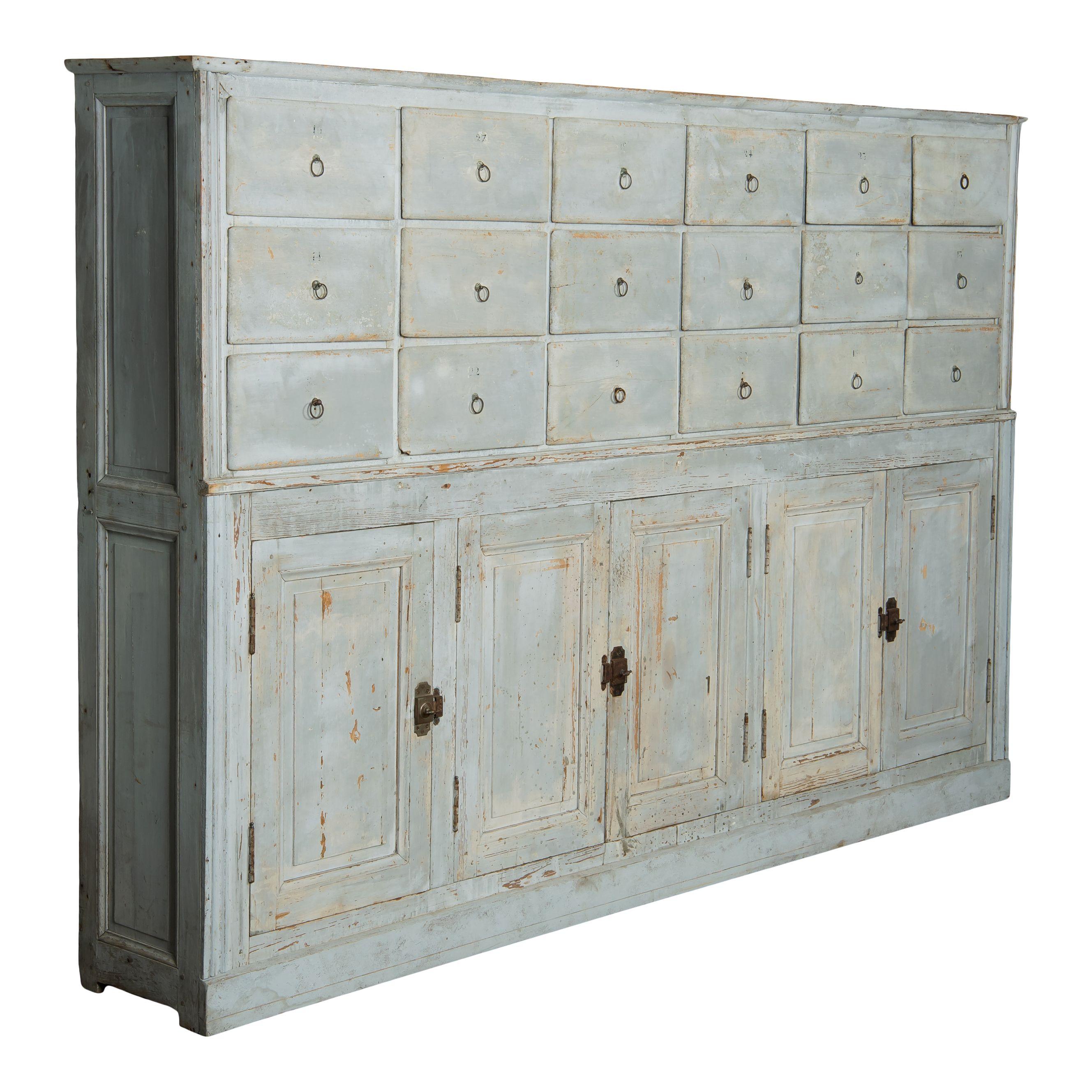 Large vintage cabinet with drawers and cabinets. There are 18 small drawers on the top half of the piece and three cabinet at the bottom, one of which has 2 shelves inside. The patina of this piece is something special, with chipping light grey/blue