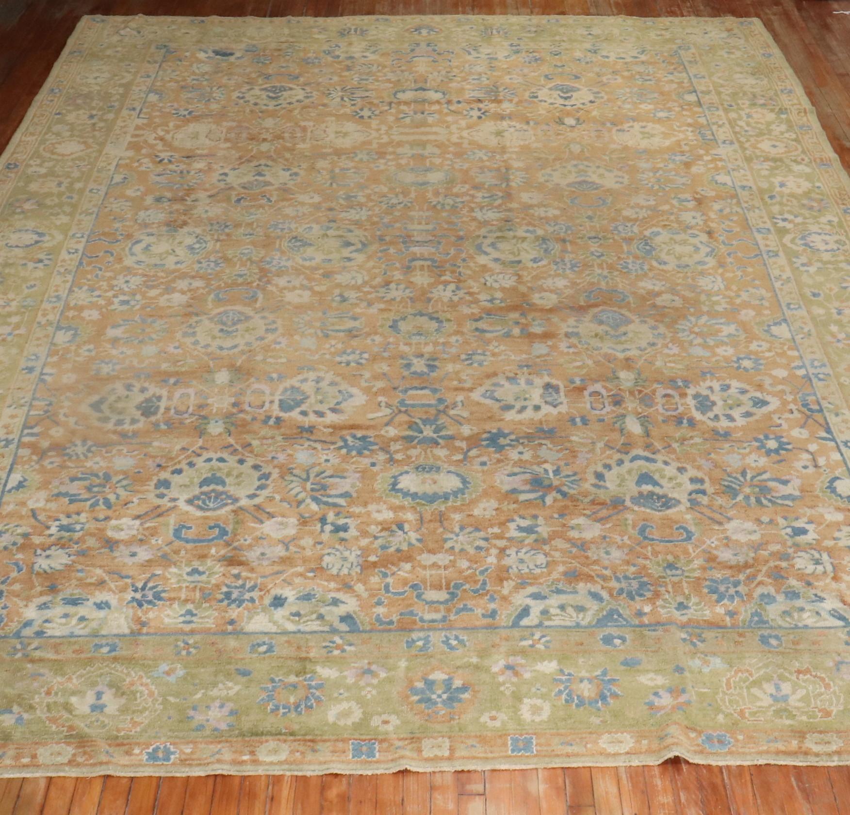 An early 20th-century oversize decorative Chinese rug with an all-over design on a faded peach field accents in brown, light blue, green, ivory. The design seems to be derived from late 19th century and early 20th century Persian Tabriz
