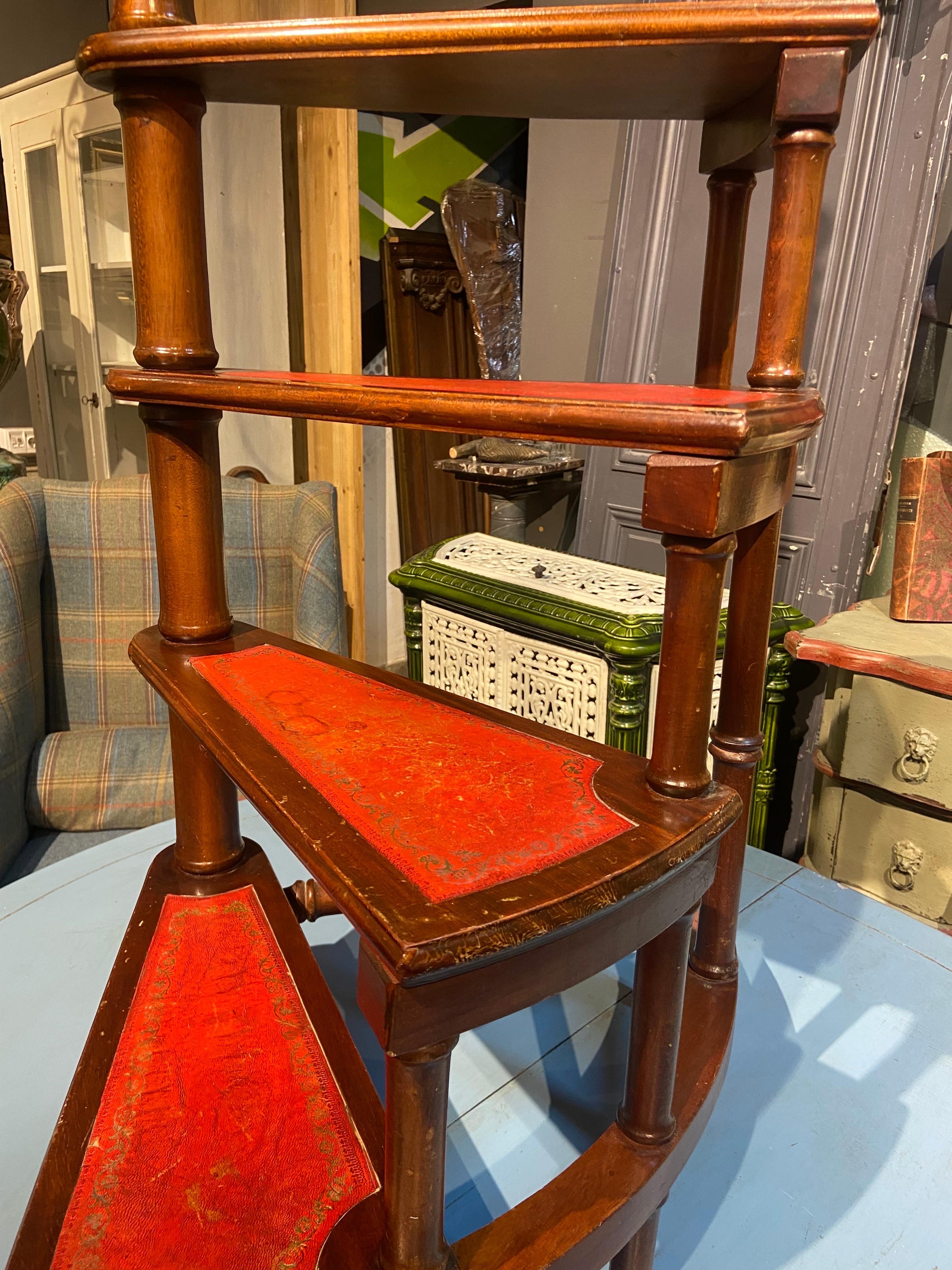 20th Century Antique round library ladder hand made of mahogany in England.

Solid wood covered with red leather at the four-stage with a long turned handle. Very stable and robust. Rare body shape. England 20th century.