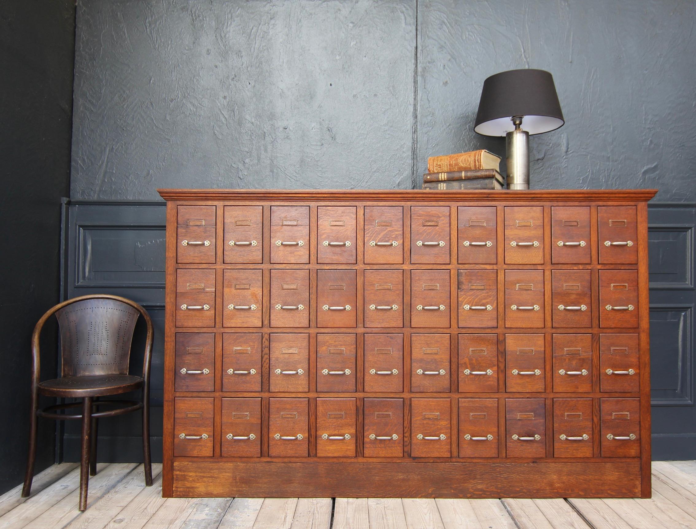 A vintage apothecary cabinet from the 1st half of the 20th century. 

Laterally coffered oak carcass with top plate and back wall of plywood. 40 drawers made of poplar wood with oak fronts. Original handles and label frames.

Dimensions: 
128 cm