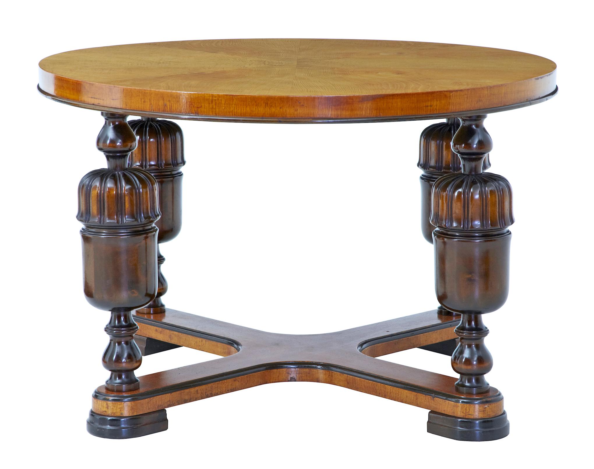 20th century Art Deco birch and elm coffee table, circa 1940.

Circular table top with matched elm veneers. Thick top is supported by 4 turned and fluted baluster legs united by an X-frame stretcher. Standing on ebonized flat hoof feet.

Minor
