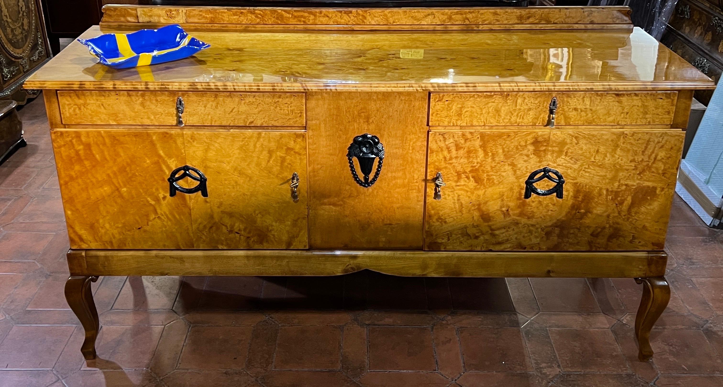 Fantastic Swedish birch sideboard, two doors and two drawers, embellished with ebonized carved wood appliqués, cabrio leg ,which gives more lightness , on the front and small riser along the entire length of the top.
Art Deco epoch, circa 1930-1940