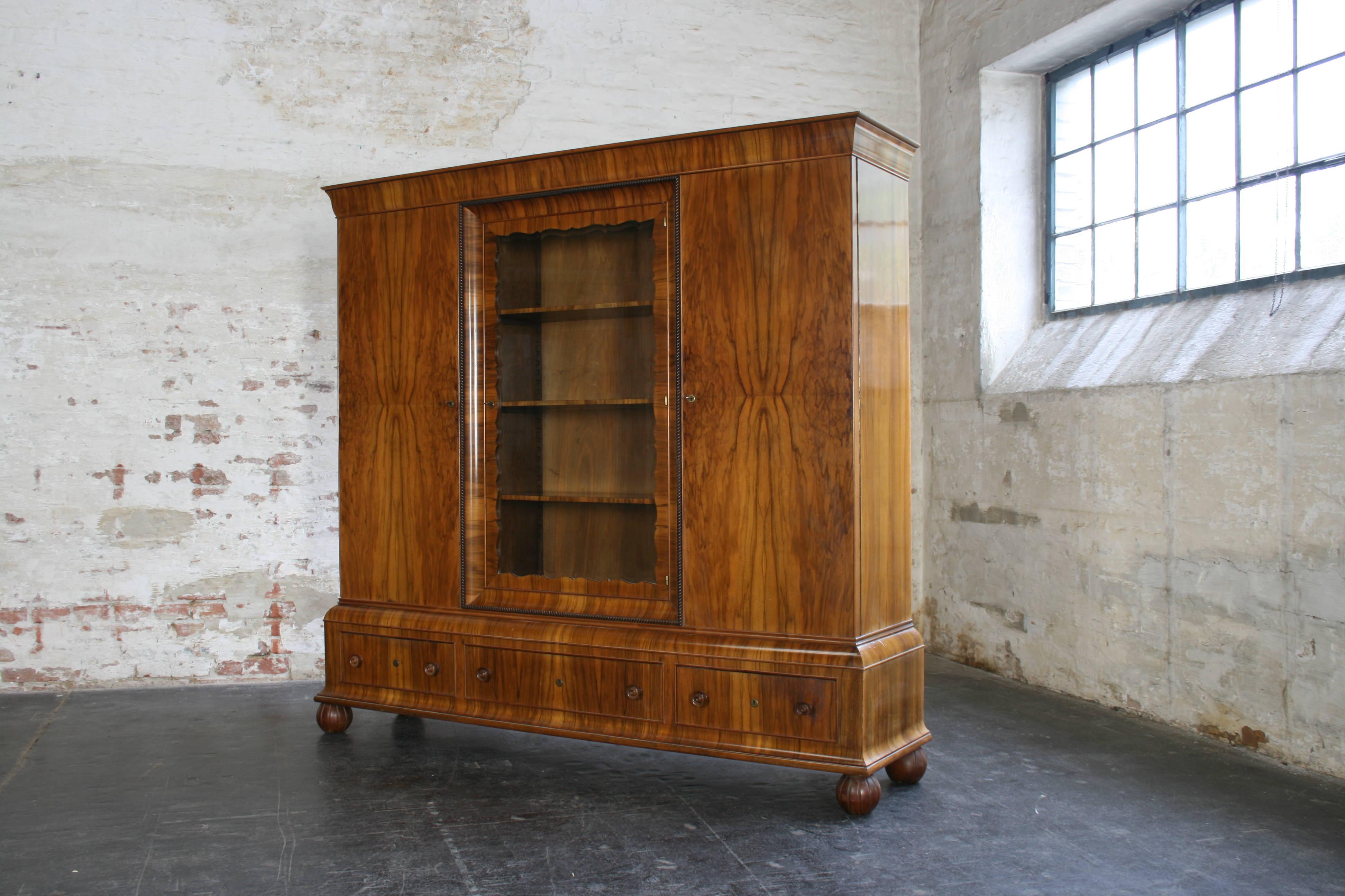 Impressive Art Deco cabinet in the manner of Otto Prutscher of Wiener Werkstätte with 2 sidedoors and a central display case with a transparent glass door showing discreet pattern of cut glass. The bottom section is structured with 3 drawers and the