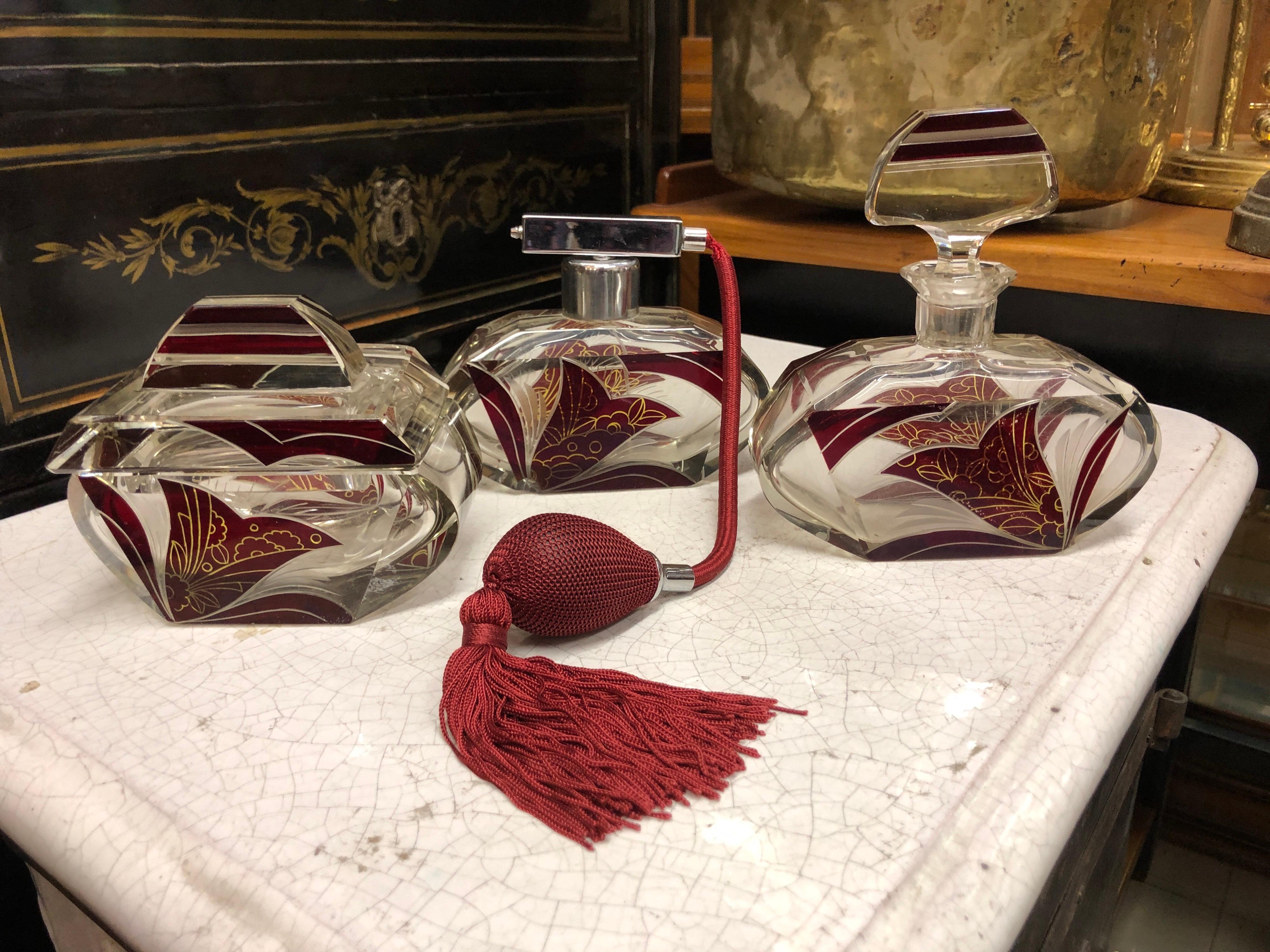 Eitelkeitsset bestehend aus Parfümflasche und Eau de Toilette-Spray und einem Seifenbehälter aus transparentem Glas und Tulpenmuster in Burgunderrot. Art-Déco-Stil
Paris, um 1920.