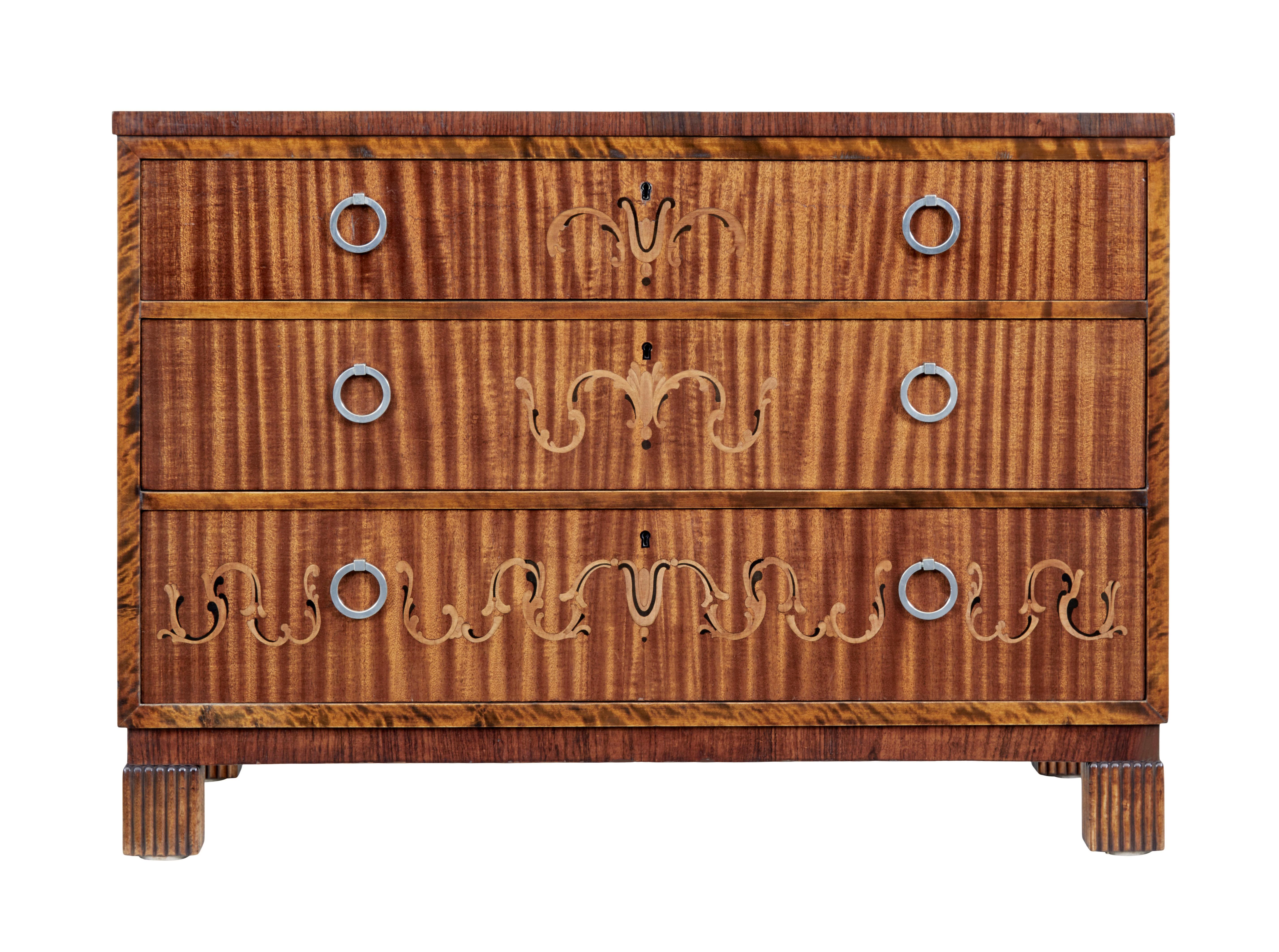 Swedish art deco chest of drawers, circa 1930.

Dark stained birch outer frame. 3 graduating mahogany drawer fronts inlaid with birch and ebonized swags, fitted with brush steel ring handles.

Standing on fluted block feet.

Minor surface marks to