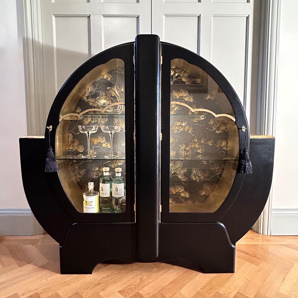 An early-20th Century Art Deco cocktail cabinet dating back to the 1930's. Totally restored and hand-painted, featuring a sleek satin black exterior while the interior has a rich contrast with gold leaf. Inside, the back panel has been decoupaged