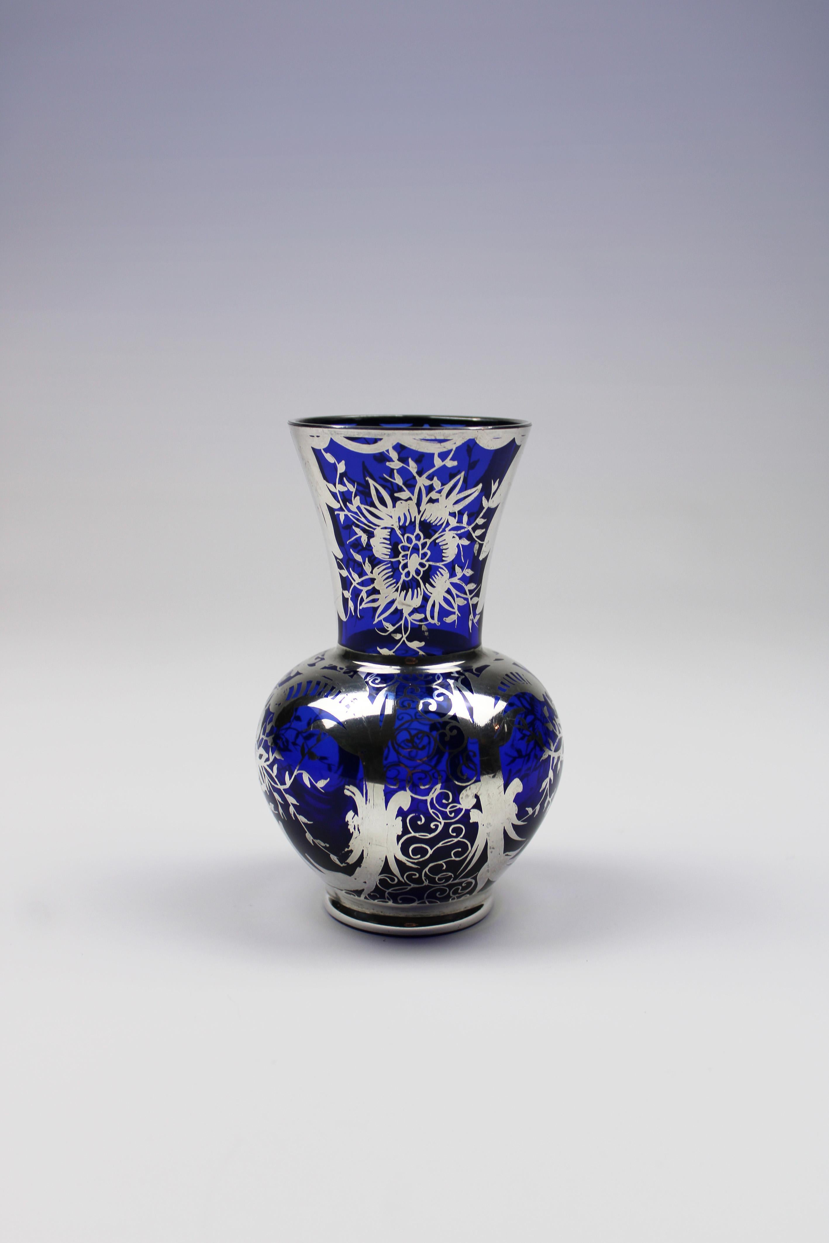 Wir präsentieren eine auffällige kobaltblaue Vase im Art-Déco-Stil, verziert mit einem exquisiten Silberüberzug. Dieses italienische Meisterwerk mit seinen eleganten Blumendekorationen zeigt die raffinierte Handwerkskunst und das stilvolle Design,