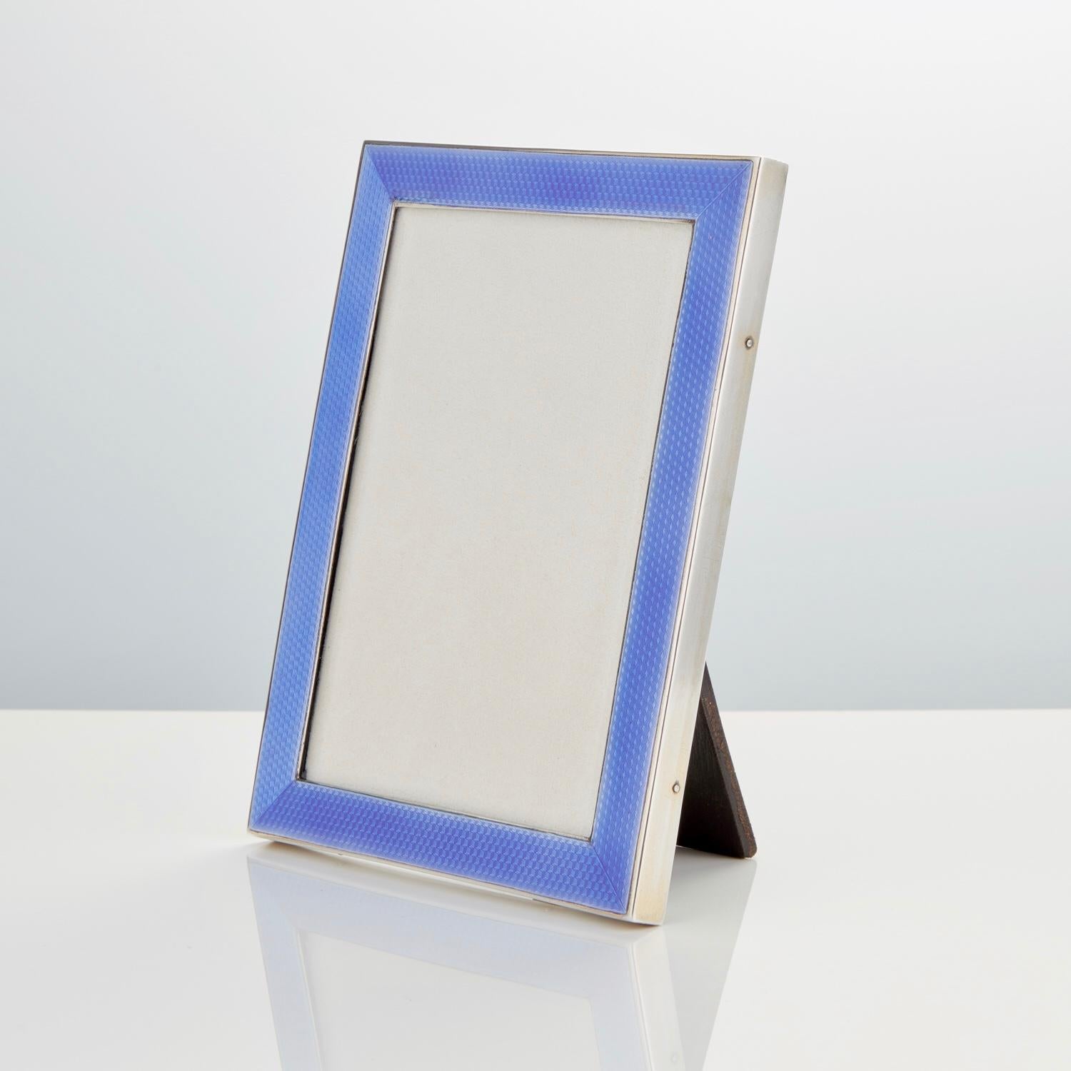 This frame is in excellent condition the enamel has an iridescent quality. The silver has a good return at the side the back & easel are in black Morocco leather.

Maker Henry Clifford Davis, Birmingham, 1929.