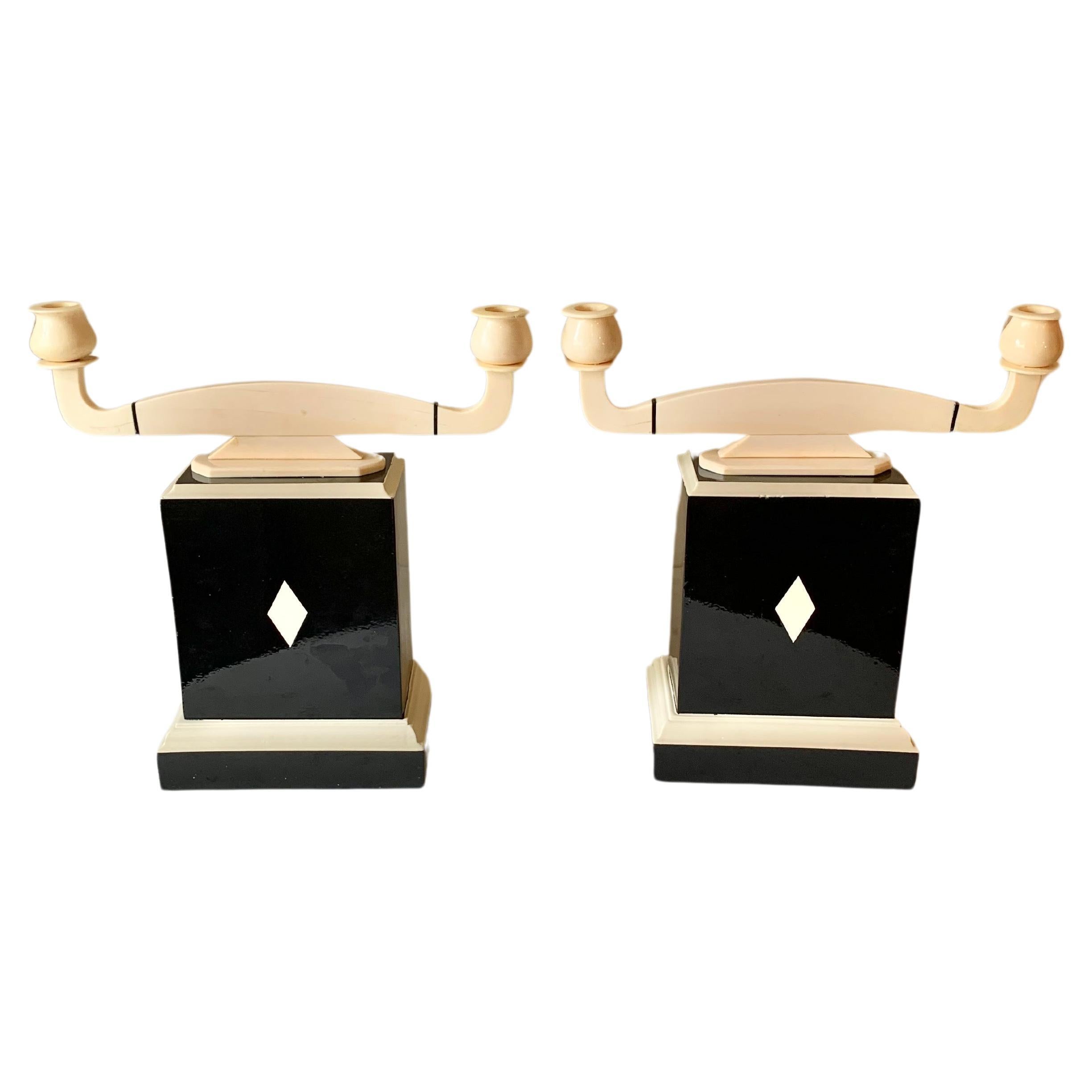 Found in England, this striking pair of Art Deco Style Candleholders were handcrafted from wood and resin by artisans in the 20th Century. The base of each candlestick is created from wood that has been lacquer painted in a black and ivory and