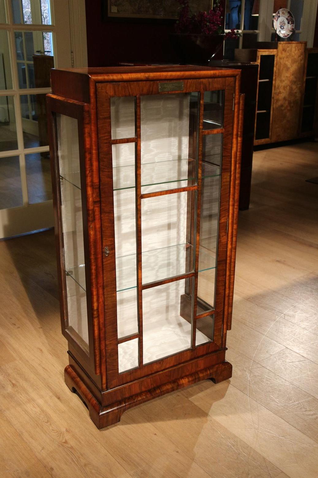 Beautiful walnut Art Deco display cabinet completely in perfect condition. This is a great example of pure art deco furniture. It is reflected in the glass design, base and construction of the sides. The brass plate indicates that it was given to