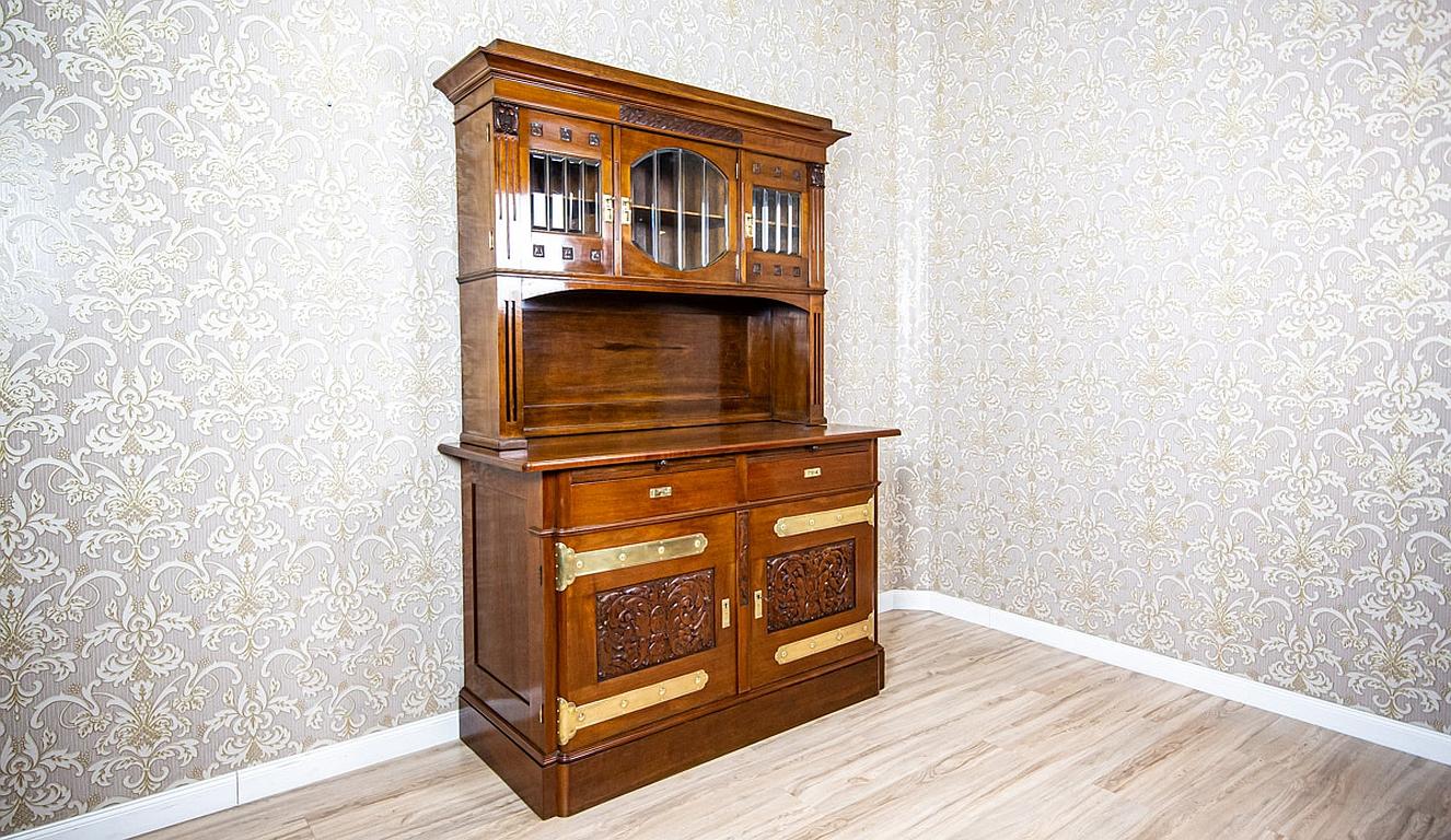 We present you this massive, high walnut buffet, circa 1900-1910.
It is composed of a two-leaf base with two drawers on the axis and a high add-on unit in the form of a wall, which is enclosed above with three glazed cabinets.
The whole is topped