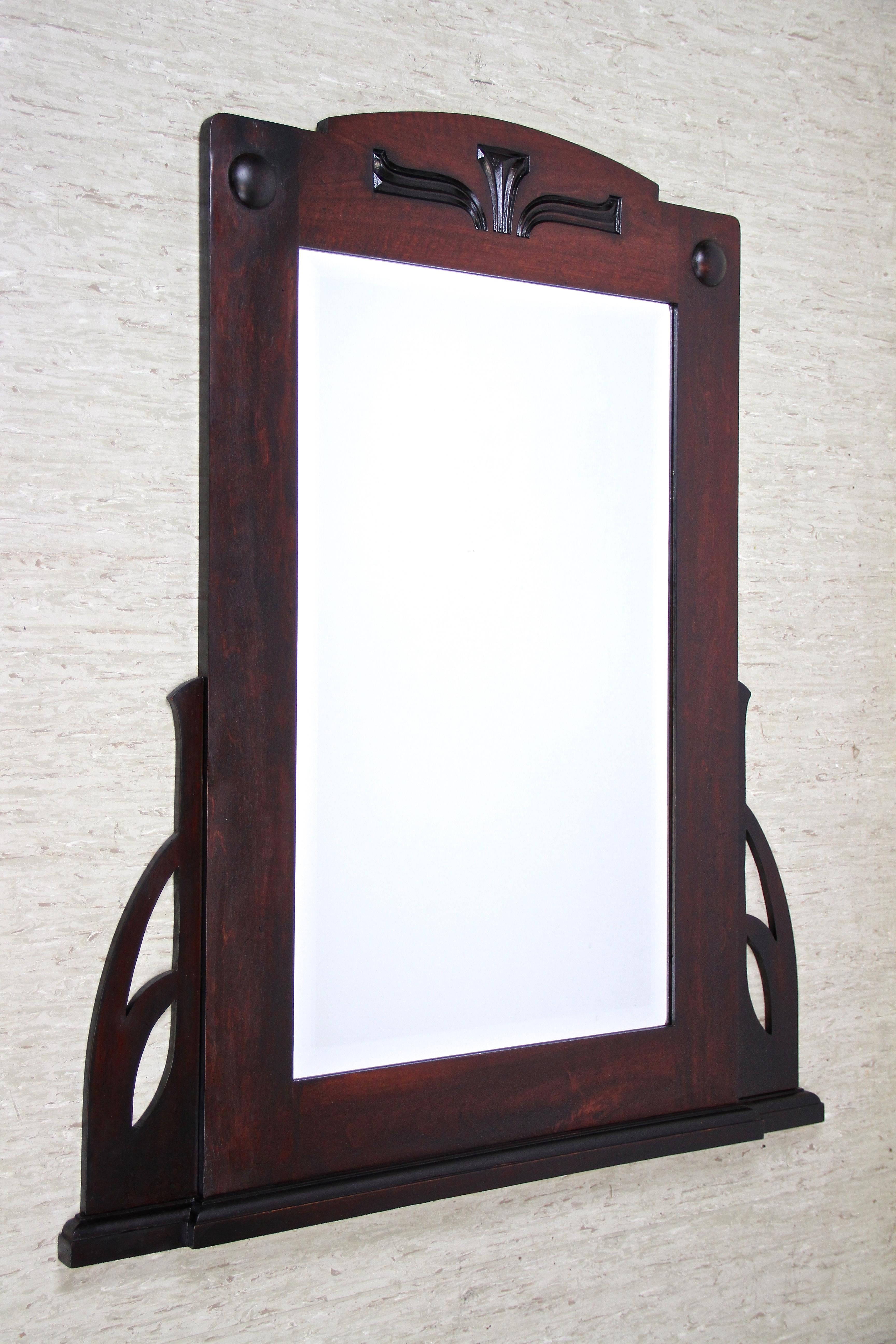 Large wooden Art Nouveau wall mirror with facet cut mirror from the period in Austria around 1905. This fantastic early 20th century mirror shows best the classical design language of this renown era. Trimmed to a very dark mahogany look, the over