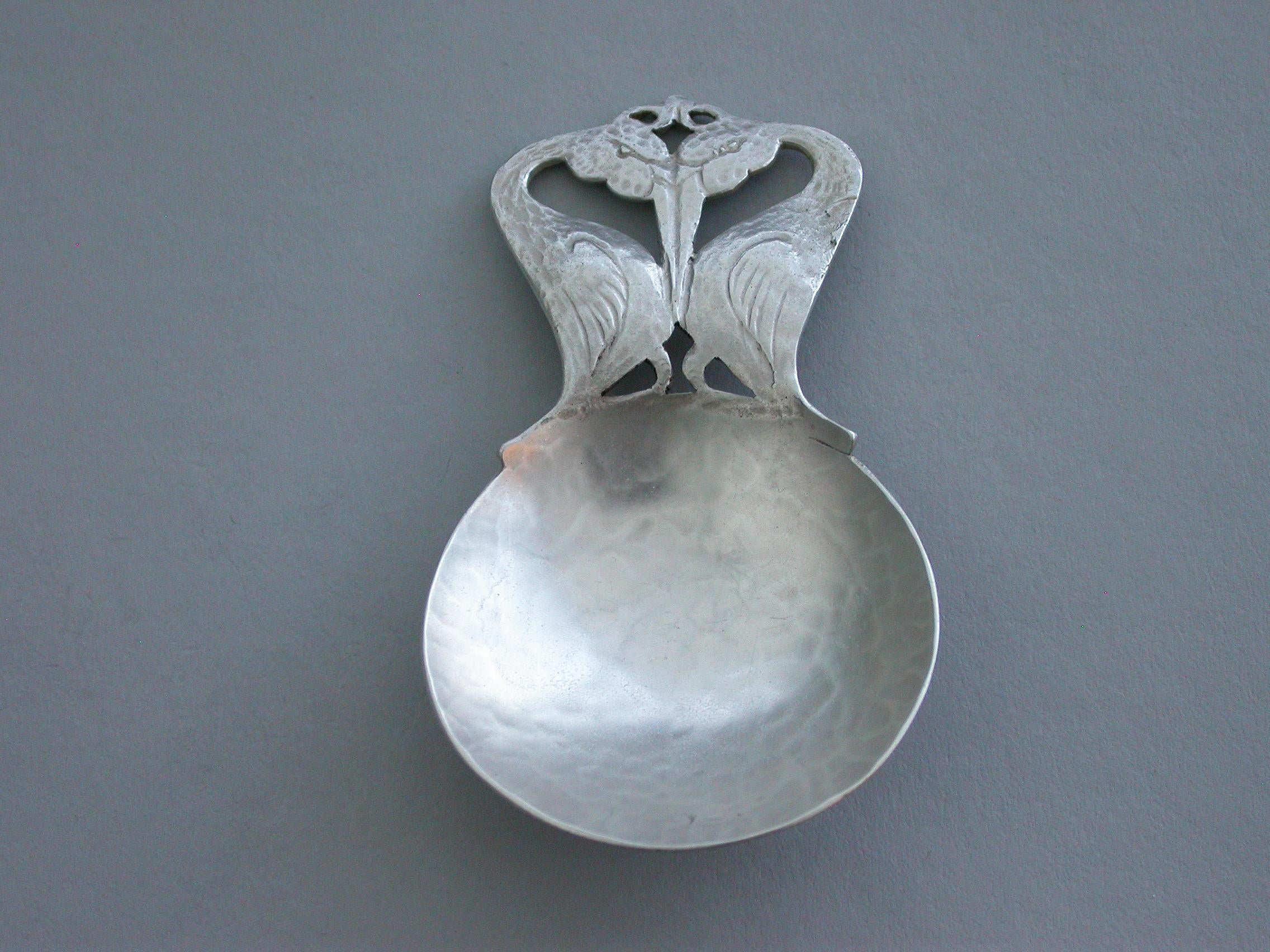 A rare early 20th century hammered silver Caddy spoon made in the Arts & Crafts style, with circular bowl and pierced handle depicting two stylized storks, sitting face to face.

By Bernard Instone, Birmingham, 1928

In good condition with no