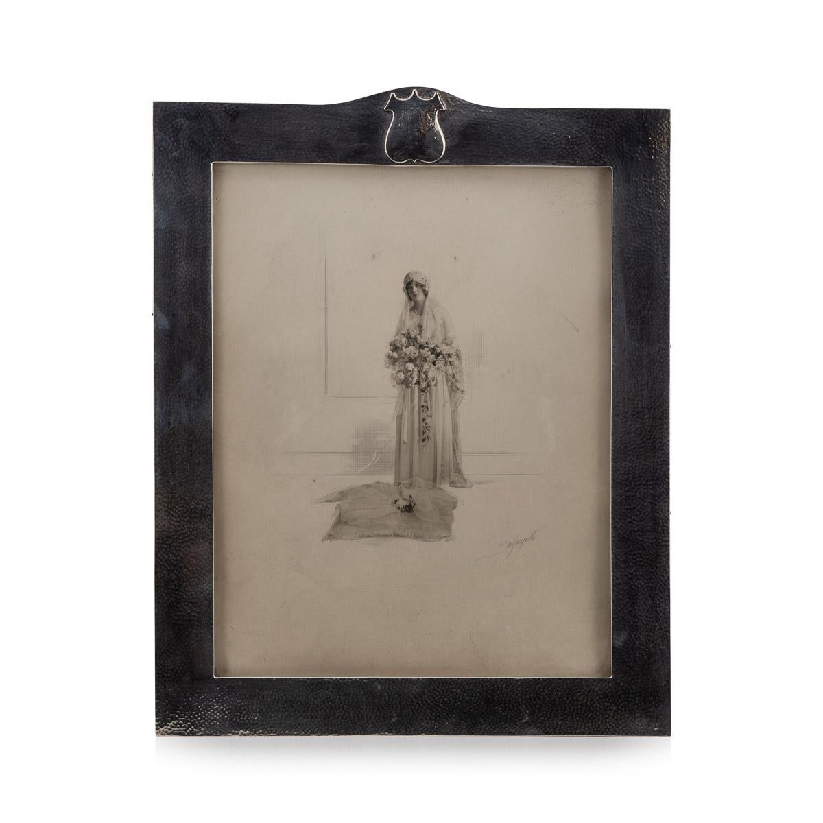 Arts & Crafts del siglo XX, marco de fotografía de plata martillada a mano, montado sobre un soporte de caballete encuadernado en cuero y engastado con cristal, parte superior con una cartela en forma de escudo, grabada con iniciales elaboradamente