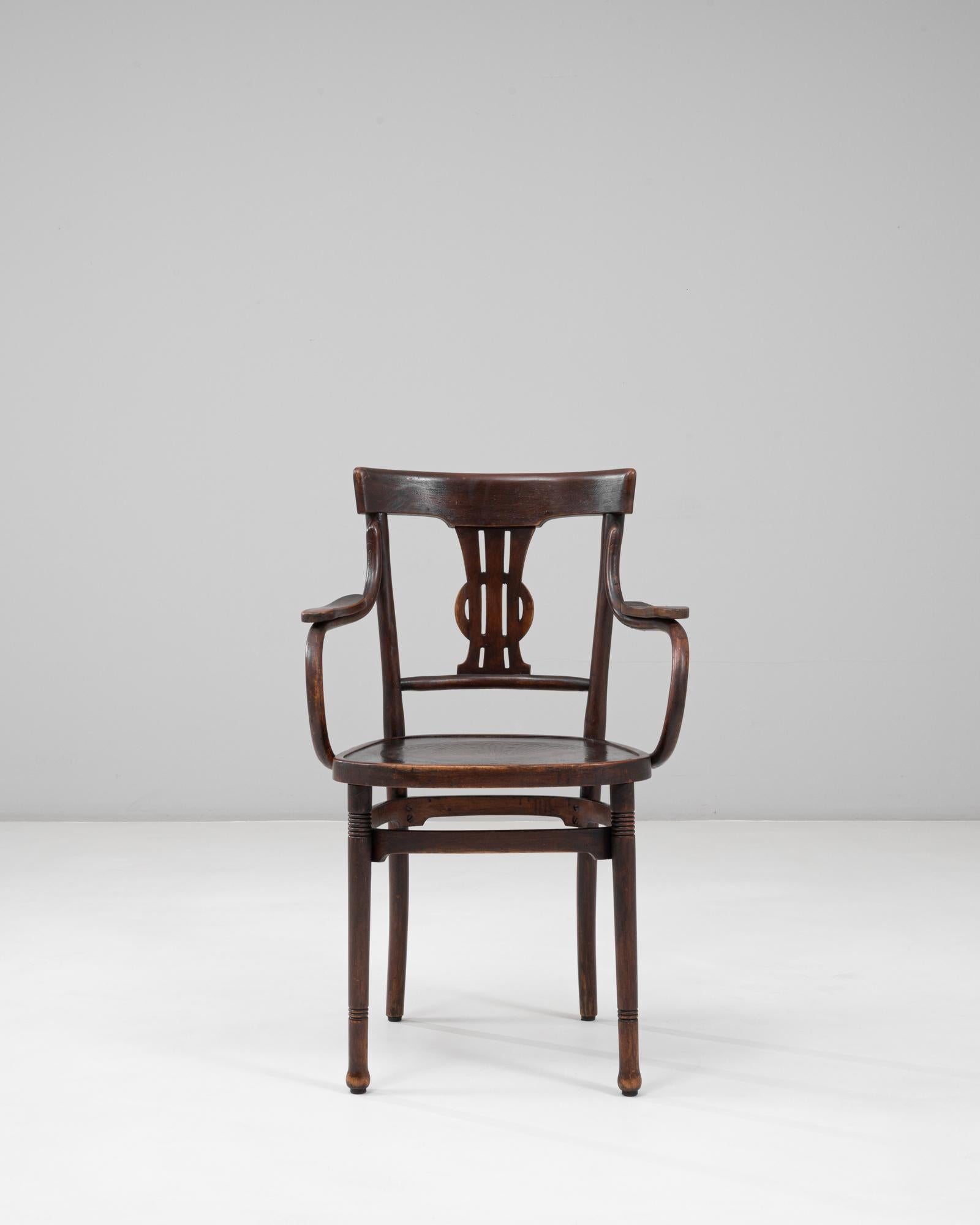 Este sillón austriaco de madera curvada del siglo XX, con un detalle en el respaldo en forma de lira, muestra maravillosamente las curvas fluidas y la artesanía sinónimo del diseño clásico vienés de madera curvada. Los brazos escultóricos y el