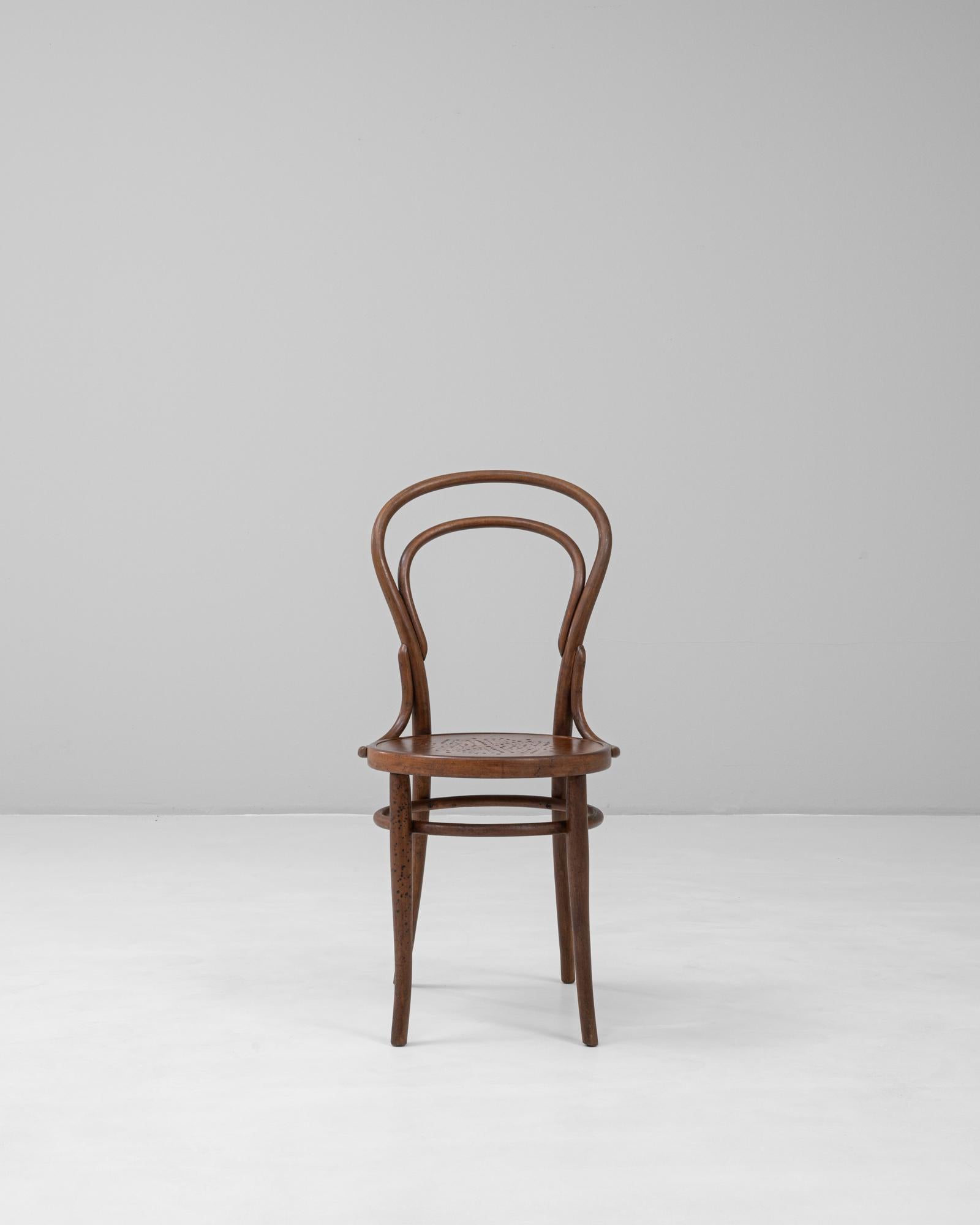 Cette chaise de bistrot autrichienne en bois courbé du XXe siècle présente le savoir-faire et l'élégance intemporels associés au style emblématique de Thonet. Fabriquée en bois courbé à la vapeur, la chaise est dotée d'un dossier incurvé et de pieds