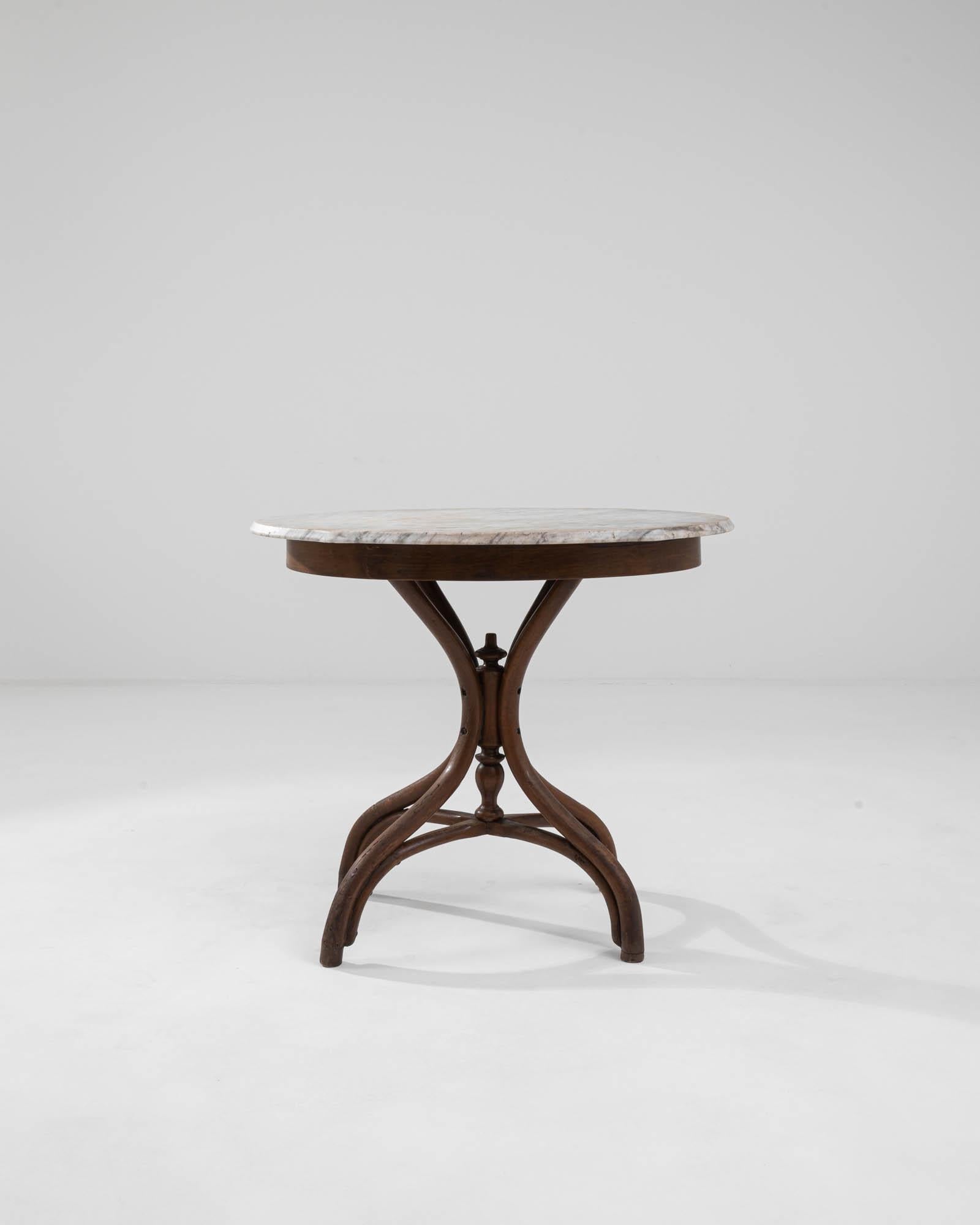 A wooden side table with a marble top from 20th century Austria, made in the style of Thonet. Four, steam-bent legs swoop downwards from this marble-topped table, elegantly joining together and then splaying apart to provide a study and eye-pleasing