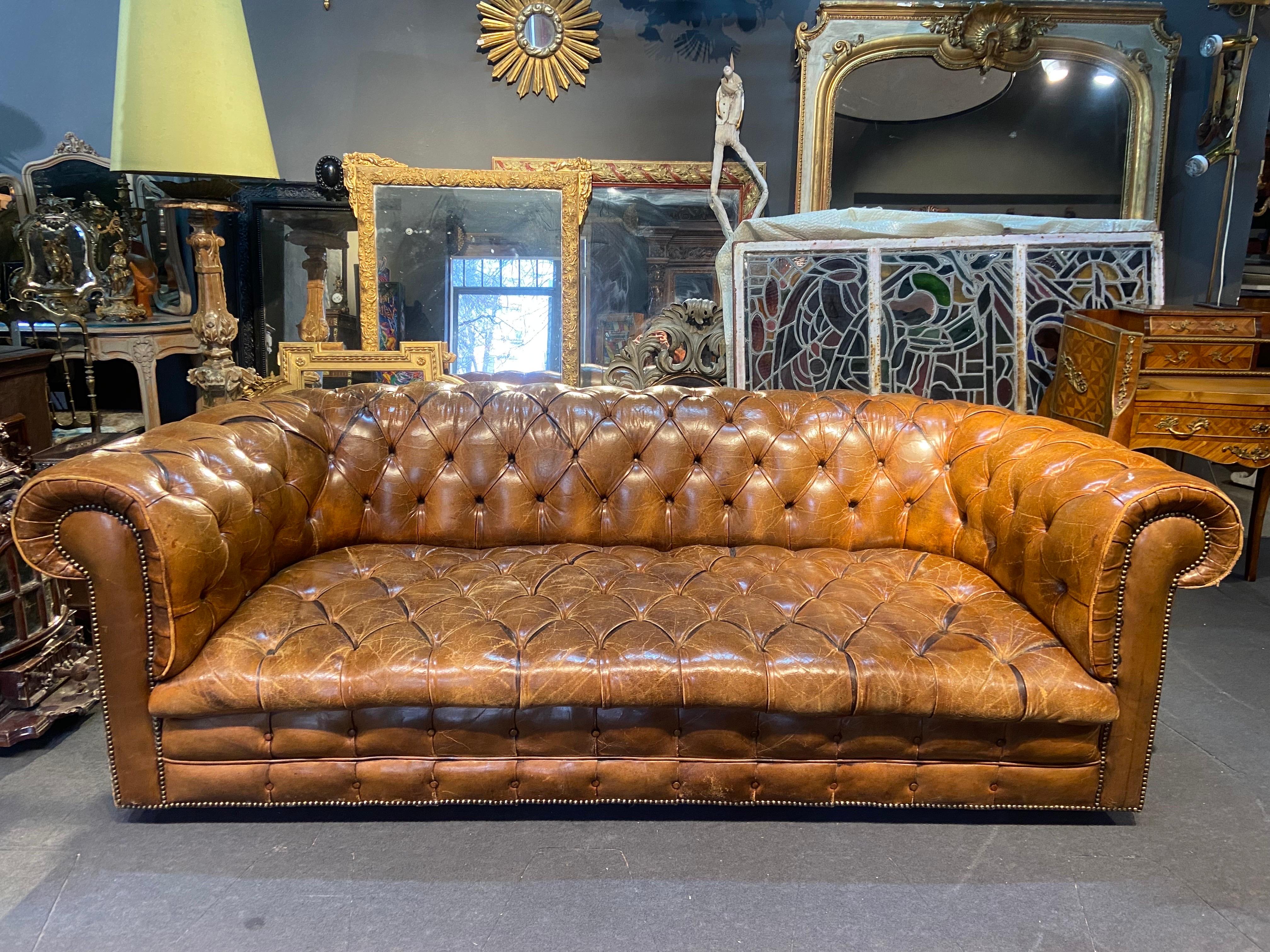 Klassisches dreisitziges Chesterfield-Sofa aus cognacbraunem Leder. Dieses traditionelle englische Sofa zeichnet sich durch ein mit Knöpfen getuftetes Interieur, überrollbare Armlehnen und auf Rollen gelagerte Beine aus. Keine Restaurierungen und