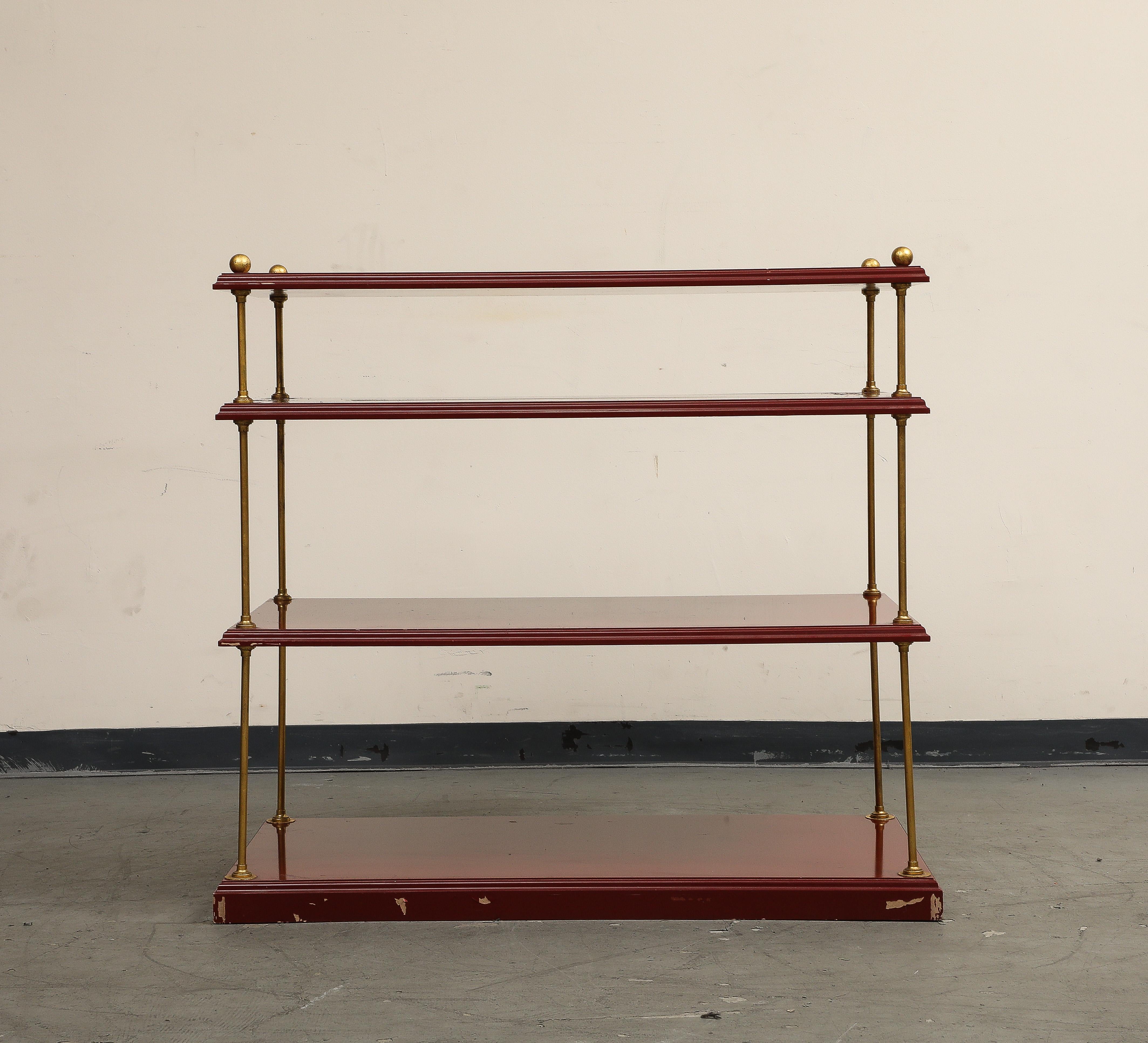 Étagère à 4 niveaux de style Baguès du 20e siècle en laque canneberge et laiton. Les supports en laiton sont surmontés d'un fleuron en forme de boule. L'état de la peinture est dégradé comme sur la photo, le prix est en conséquence. La pièce est