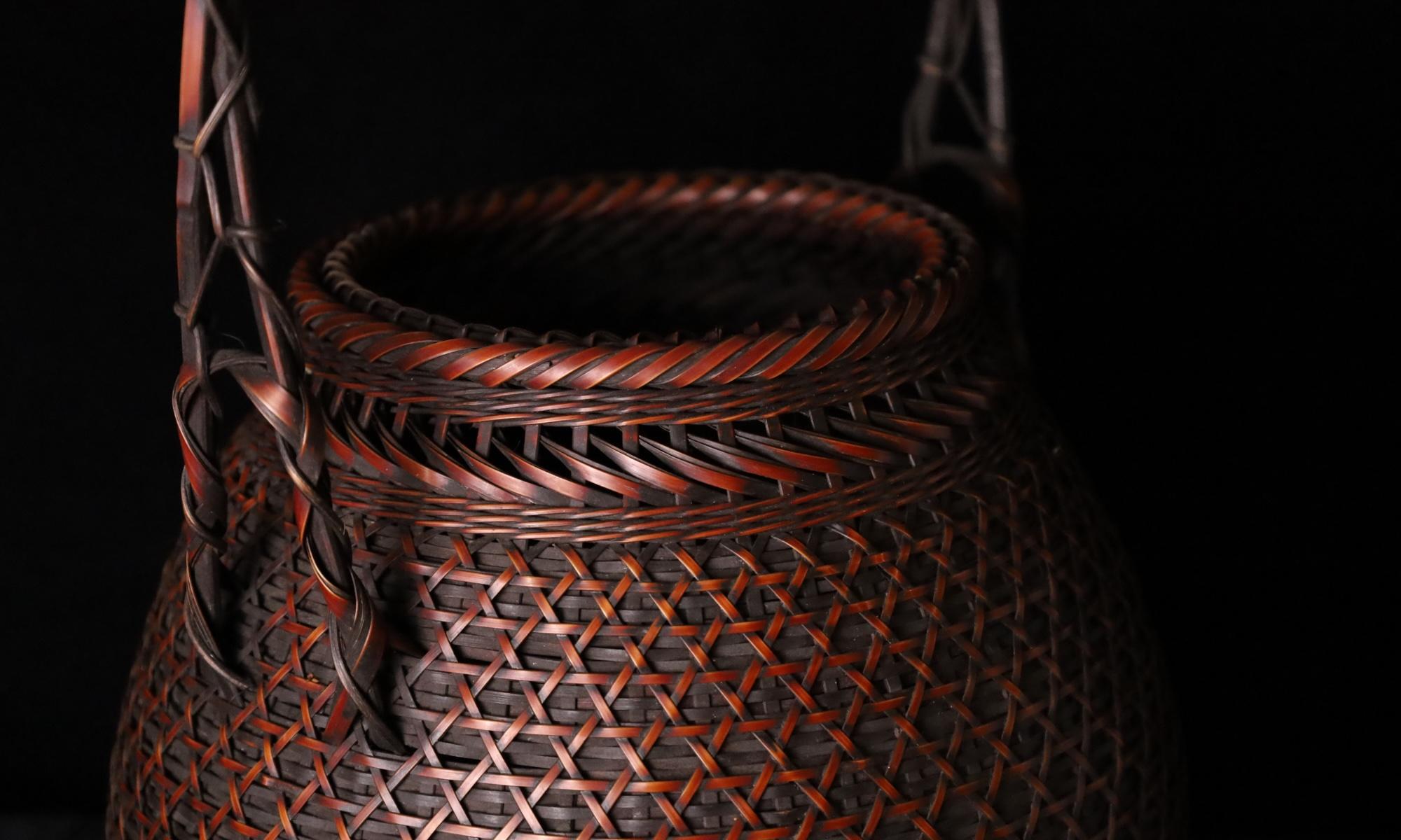 A vintage Japanese ikebana basket, crafted from lacquered bamboo using traditional basketry techniques, dating to the first half of the 20th century. This elegant piece embodies the delicate artistry of bamboo weaving, featuring  a gracefully arched