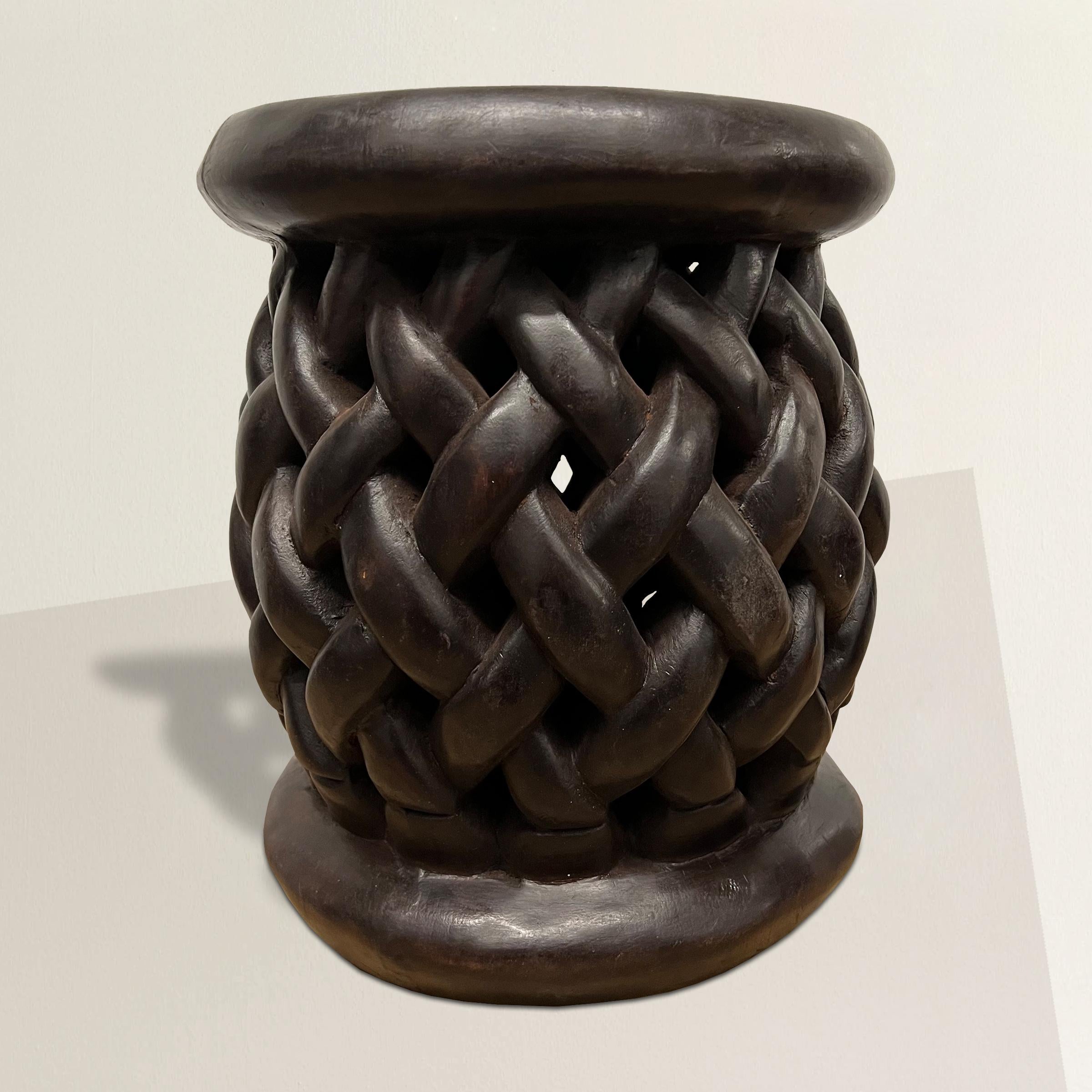 A bold and lively 20th century Bamileke stool hand-carved of one piece of wood with a beautifully designed basket-weave pattern, and with a rich patina that only time can bestow. The stool also doubles as a side table next to your favorite armchair.