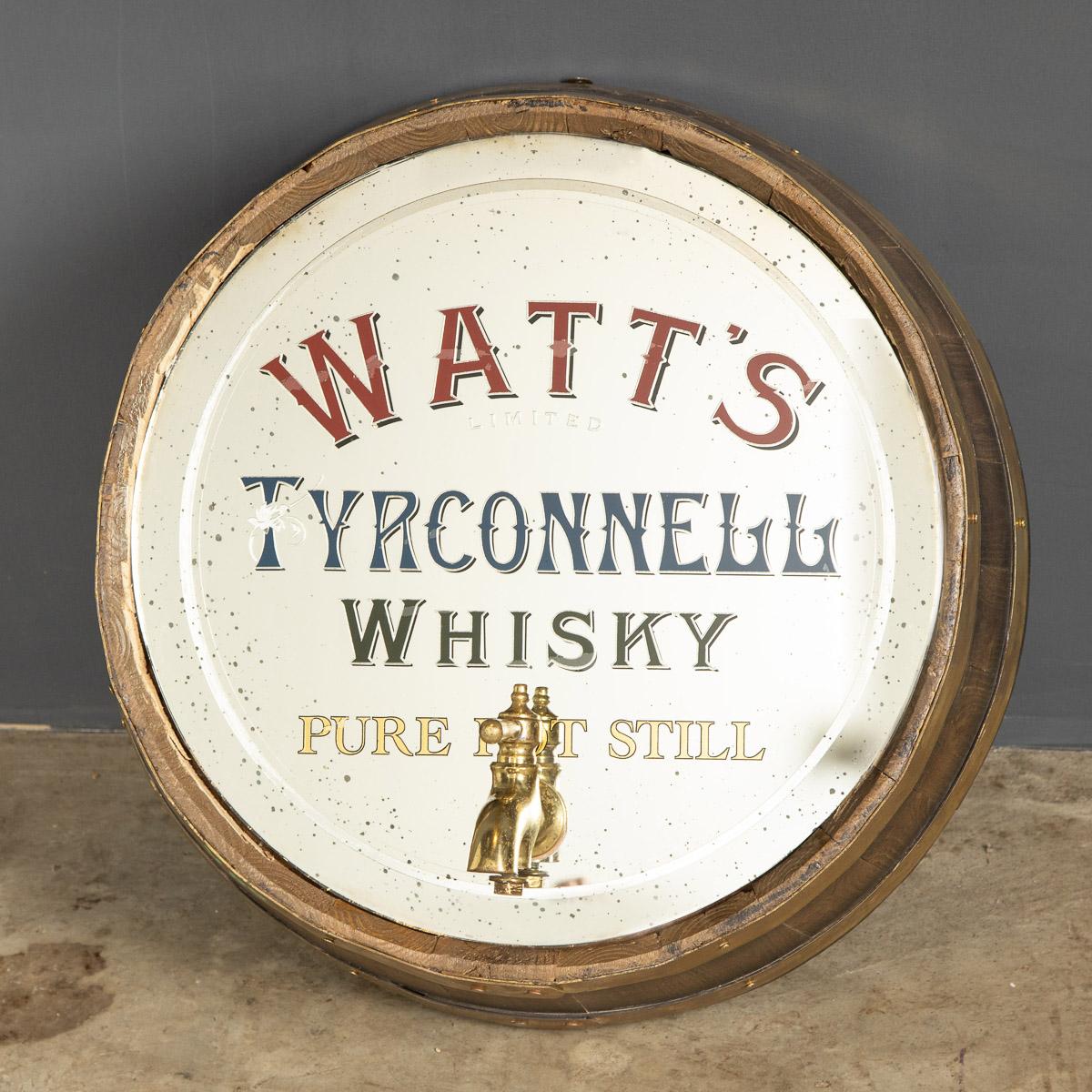 Antique 20th century rare advertising mirror. This Watts Irish Whisky mirror has been framed in a slice of an oak barrel with a decorative brass tap at the bottom. The Watts Distillery was founded by The Watt family in 1762 the Tyrconnell Whisky was