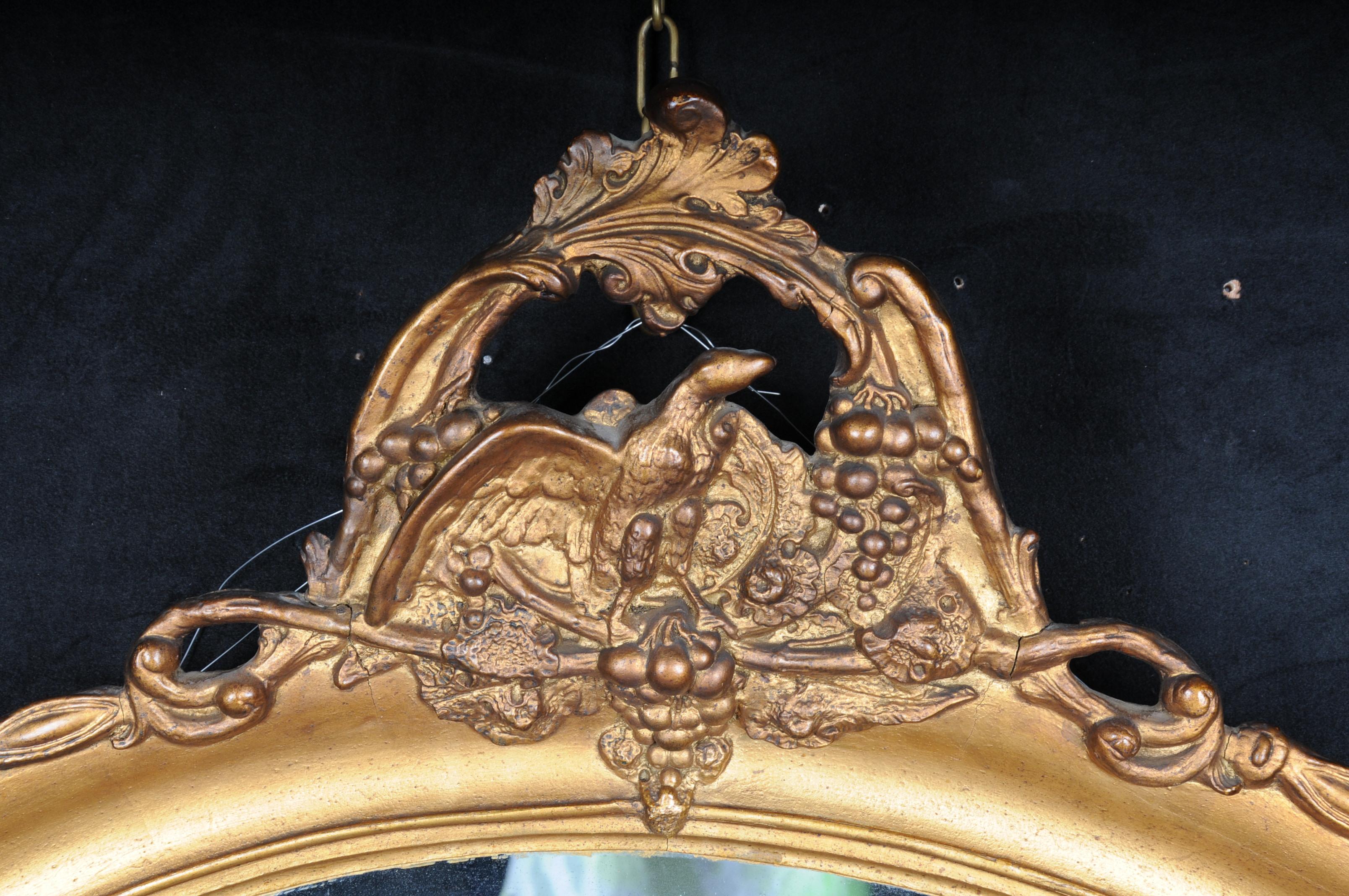 20th century Beautiful oval wall mirror, gold

Oval framed wall mirror, gilded wood/stucco. Frame crowned with an eagle on rocaile accents.
Crossed torches in the classical manner.