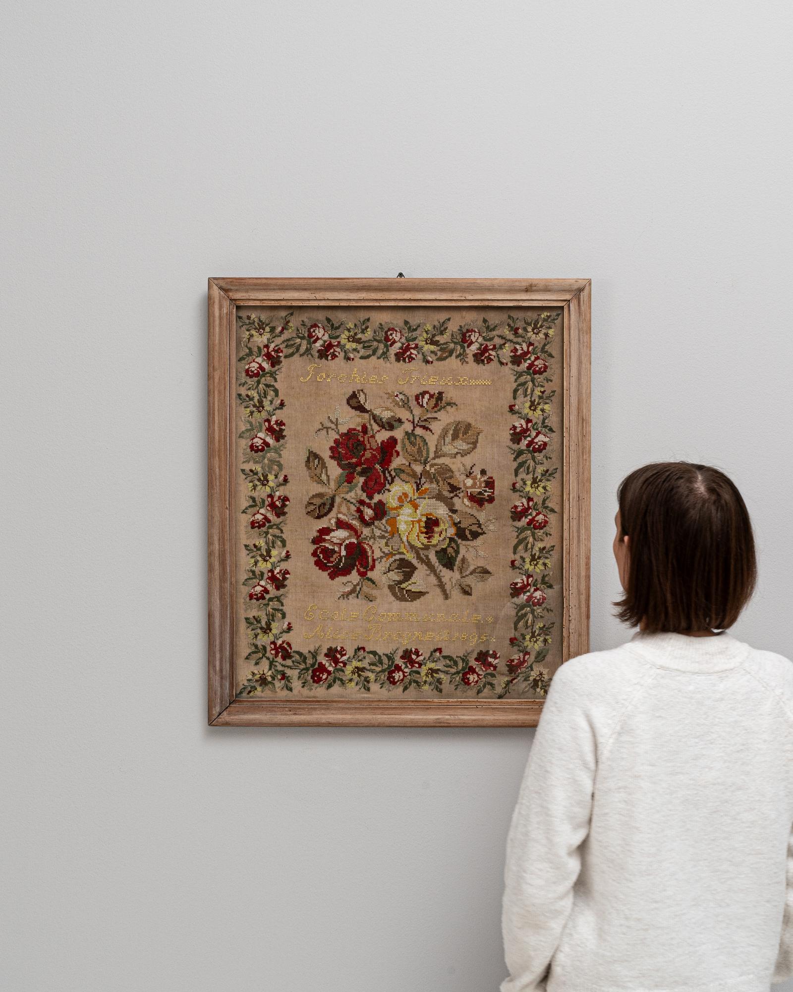 This 20th Century Belgian tapestry is a picturesque tableau of needlework artistry, beautifully framed in natural wood that echoes the warmth of the intricate stitches. It features a lush bouquet of florals, each petal and leaf meticulously