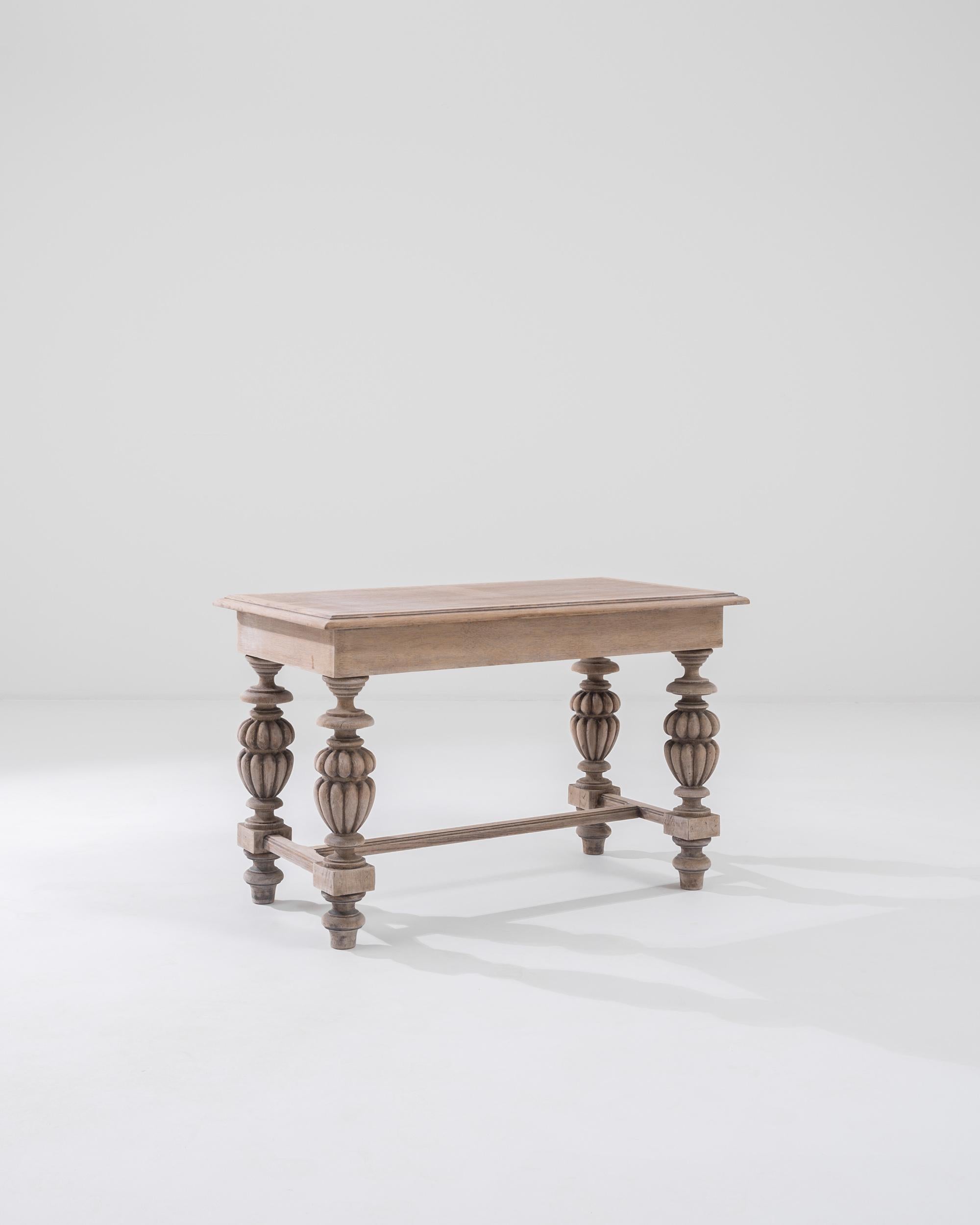 Cette table basse du 20e siècle, fabriquée en Belgique, est composée d'un plateau rectangulaire reposant sur des pieds somptueusement tournés. Méticuleusement travaillés, les pieds en forme de cucurbitacée offrent un généreux contraste avec le cadre