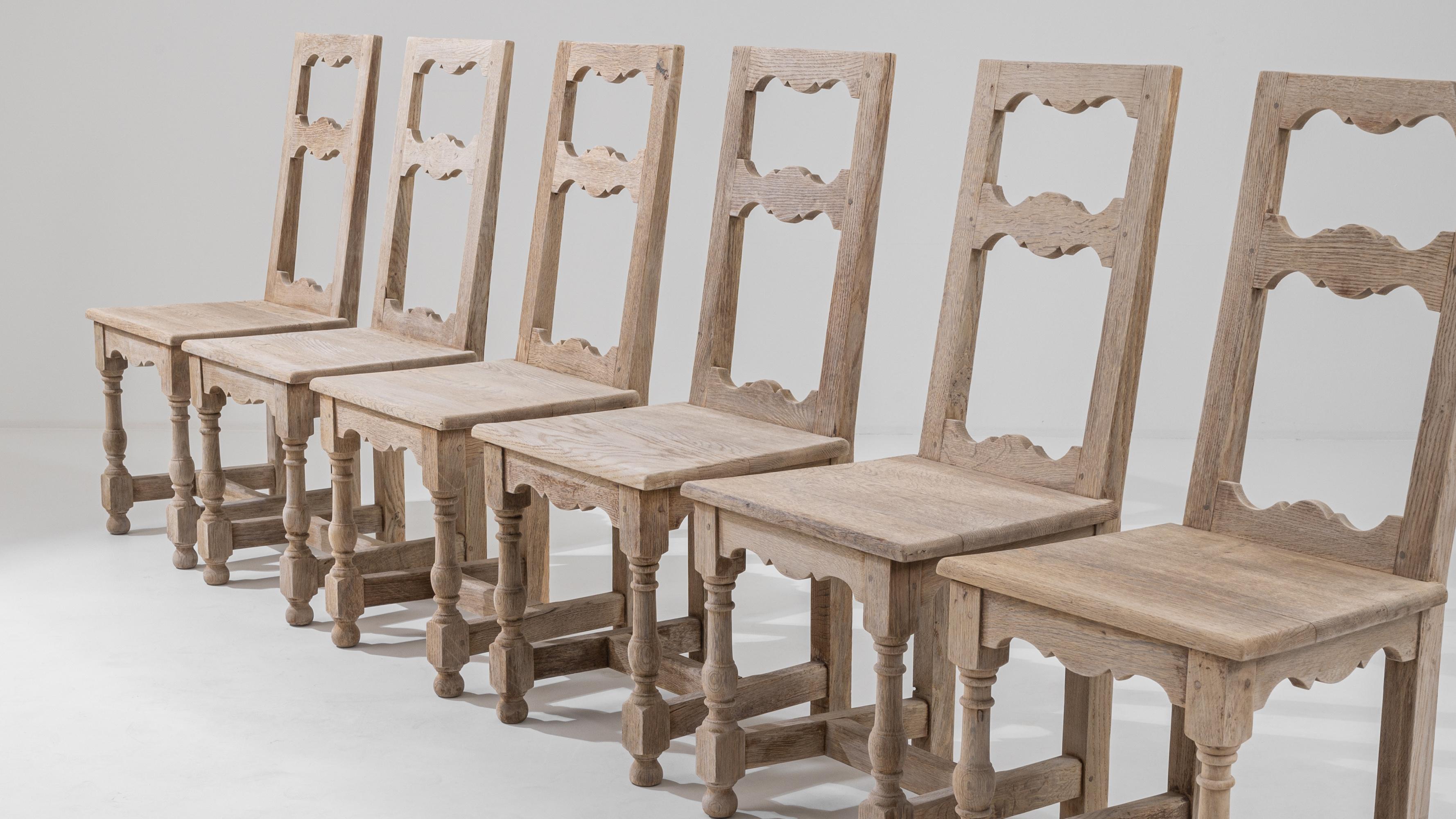 Enchant your dining space with this set of six 20th Century Belgian Bleached Oak Dining Chairs, a testament to exquisite craftsmanship and timeless appeal. Each chair is a work of art, beautifully hand-carved to showcase intricate details. The