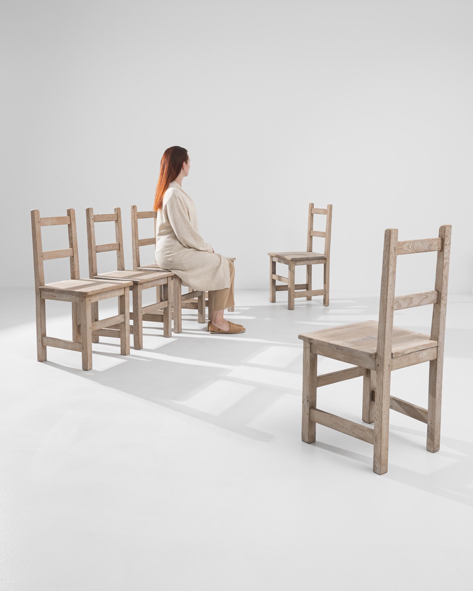 Entdecken Sie rustikale Raffinesse mit diesem Set aus sechs belgischen Esszimmerstühlen des 20. Jahrhunderts, die aus gebleichter Eiche gefertigt sind. Jeder Stuhl besteht aus einem soliden, robusten Rahmen mit einer natürlichen Lackierung, die die