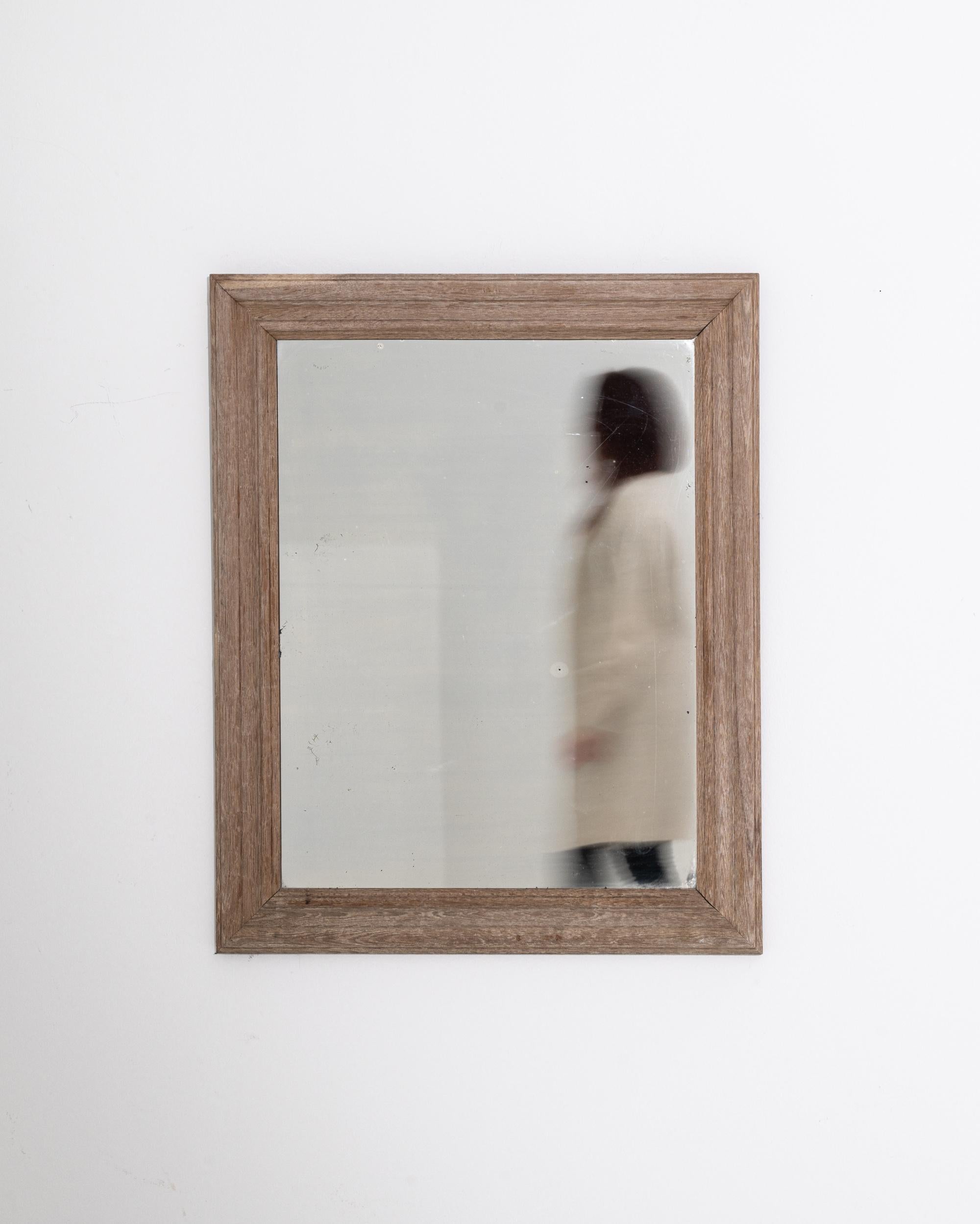 This 20th Century Belgian mirror, framed in beautifully bleached oak, brings a serene and rustic charm to any room. The light, washed-out finish of the oak frame highlights the natural grain, giving it a gentle, weathered look that complements a