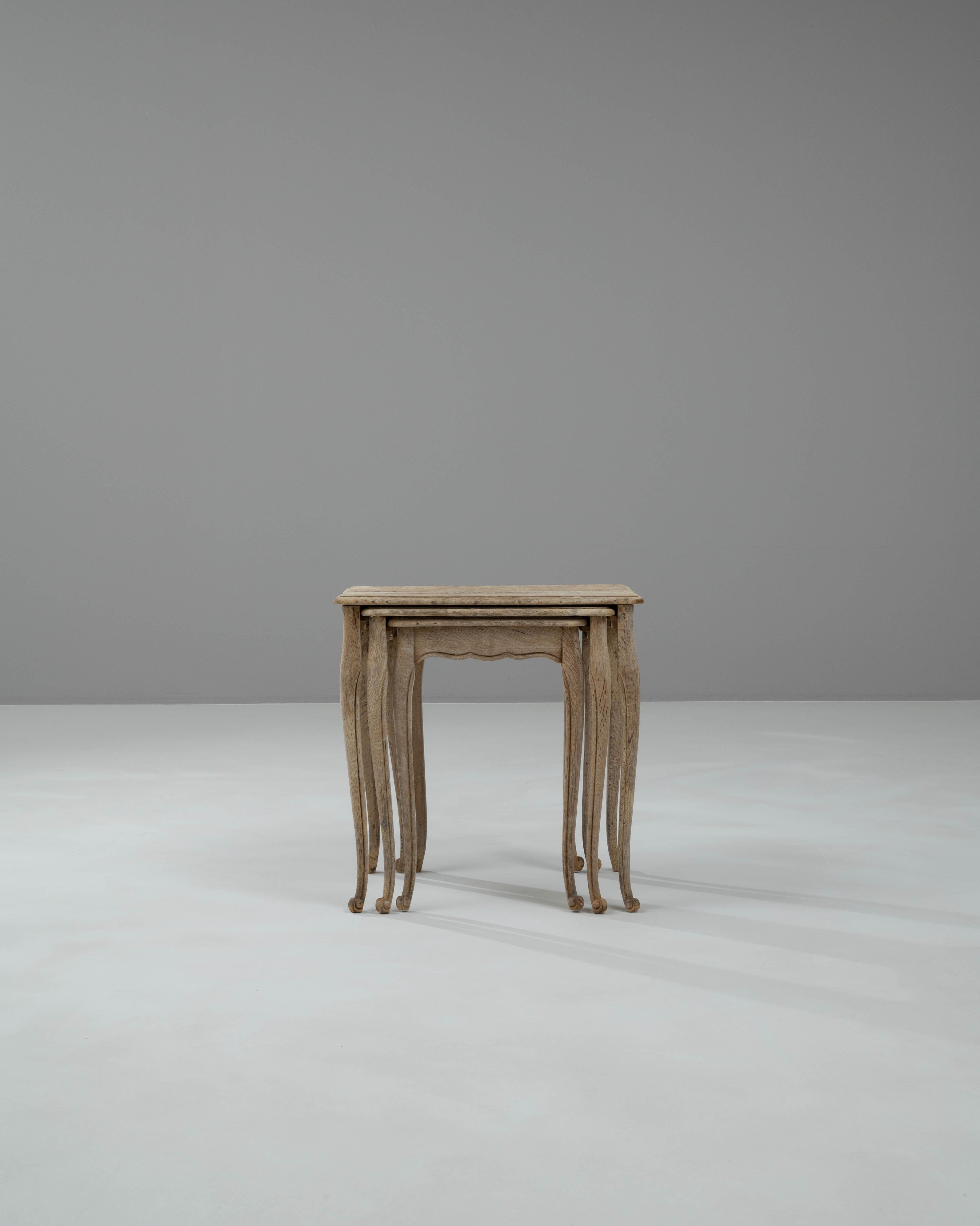 Introducing a delightful trio of 20th-century Belgian bleached oak nesting tables, each uniquely designed to offer both style and functionality in your living space. These charming tables are crafted with fine attention to detail, featuring