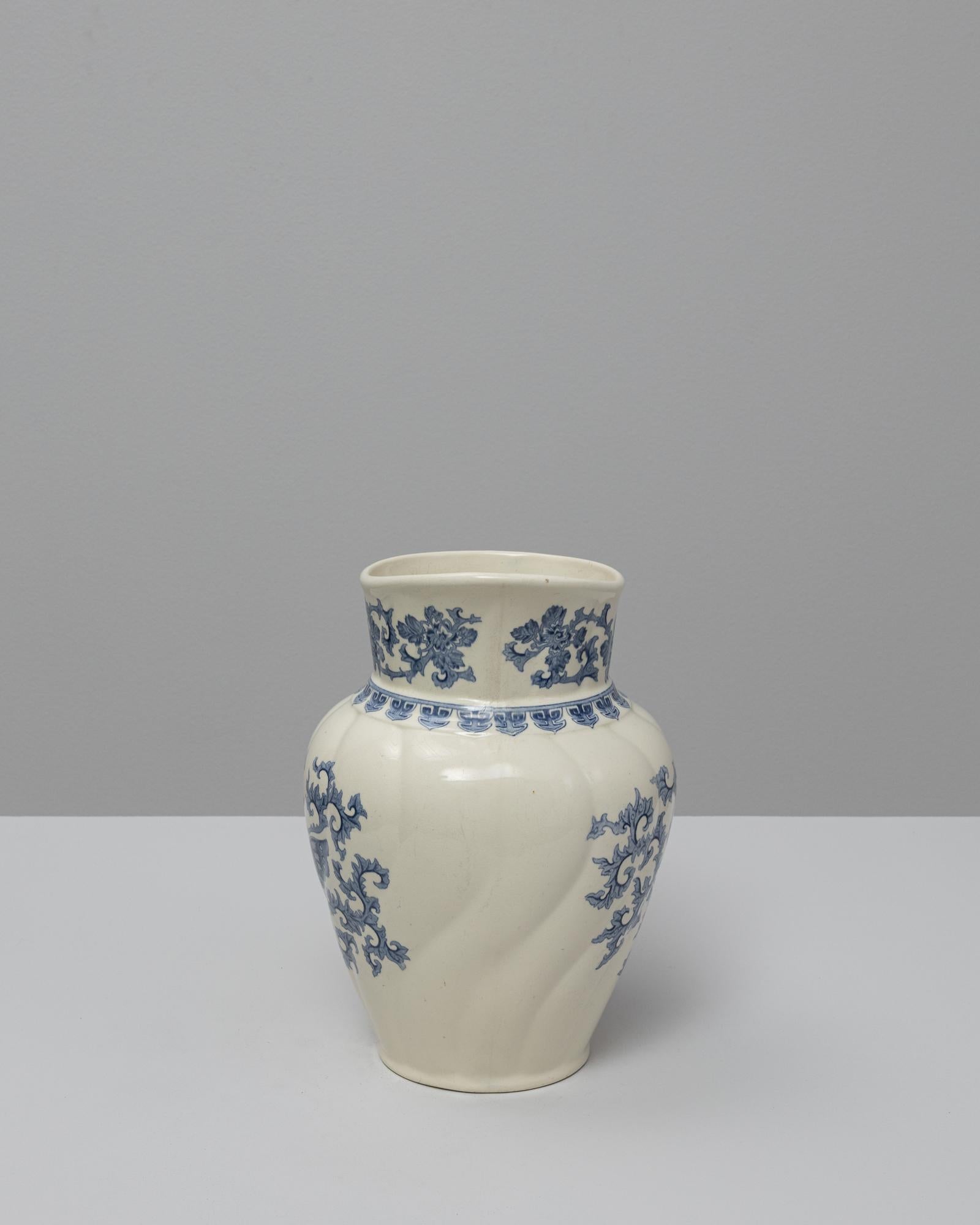 Ce pichet en céramique Chinoiserie bleue belge du 20e siècle présente une silhouette gracieuse enrichie de délicats motifs d'inspiration orientale. Le corps doucement arrondi s'élève en un bec évasé et asymétrique, offrant à la fois élégance et