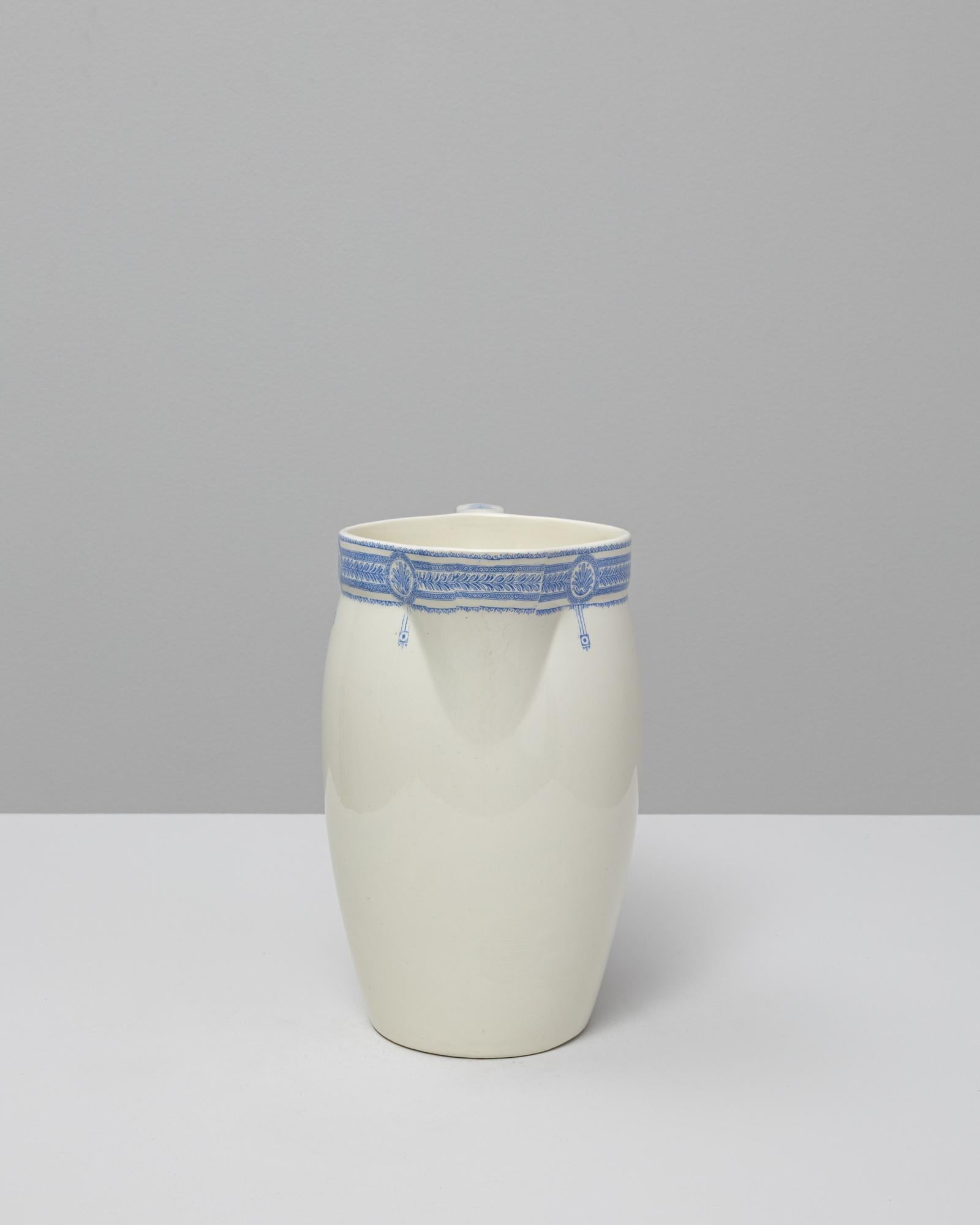 Questa brocca in ceramica belga blu Silhouette del XX secolo presenta una silhouette raffinata e minimalista, arricchita da una delicata fascia di ornamenti di ispirazione orientale. Il corpo affusolato e la bocca delicatamente svasata creano una