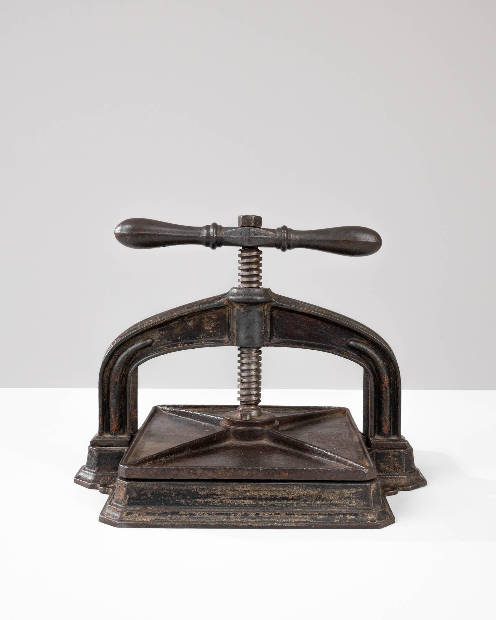 A cast iron press from 20th Century Belgium. Originally purposed as a book-binding press used in such places as banks or libraries, this unique antiquity suggests a niche function, while providing a universal visual appeal. Its cast iron form,